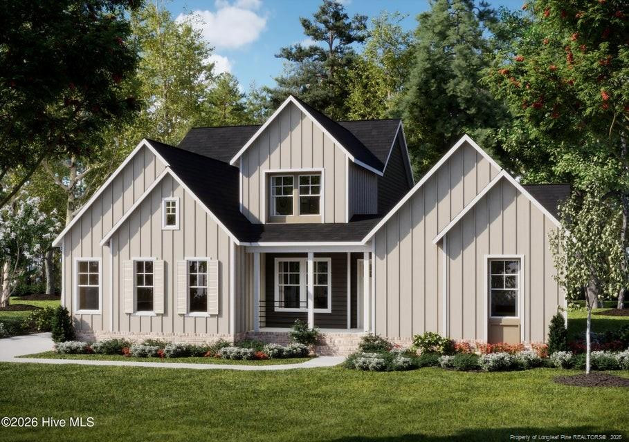 Light gray gabled home with a covered front porch, flower beds, and a broad green lawn.