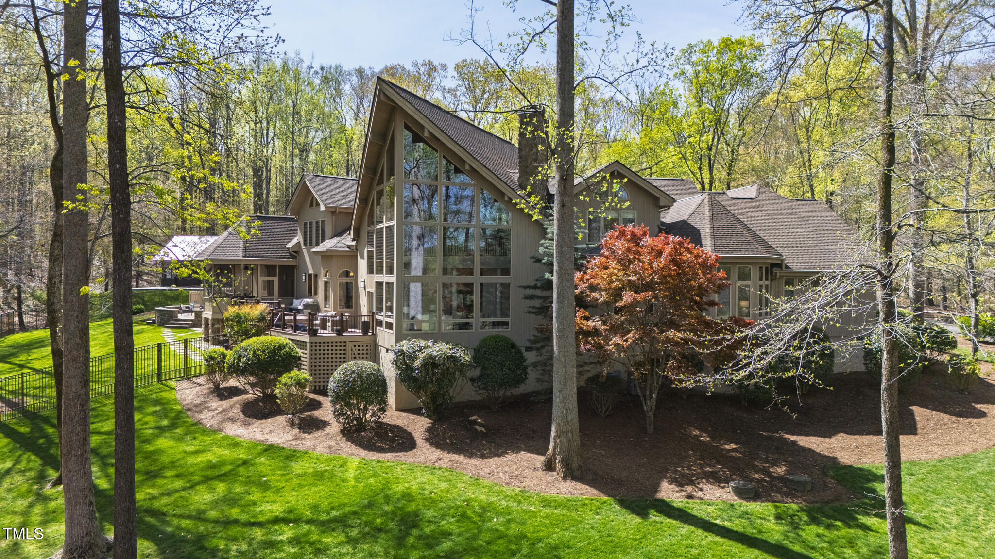 Contemporary home with expansive windows and a steep roof, surrounded by trees and landscaped lawn.