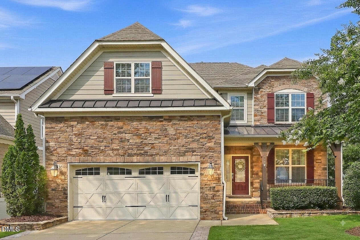Two-story stone-front house with a cream garage door, red shutters, and a covered front porch.