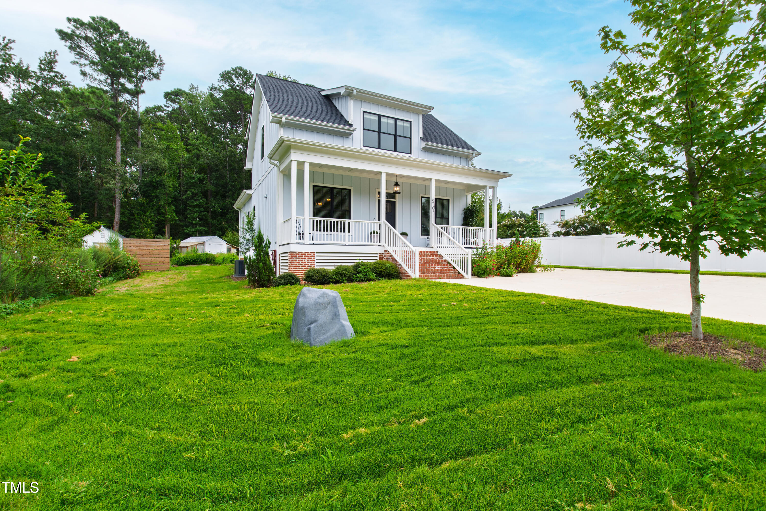 White two-story house with a covered porch, brick foundation, and broad green lawn.