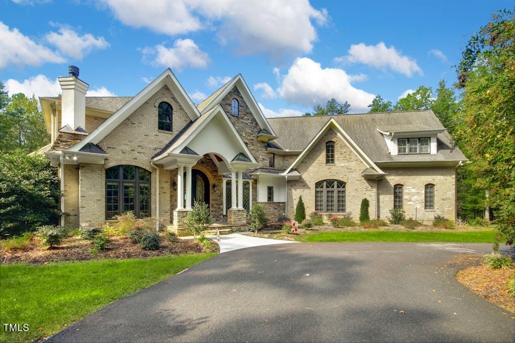 Stone house with multiple gables, arched windows, and a curved driveway.