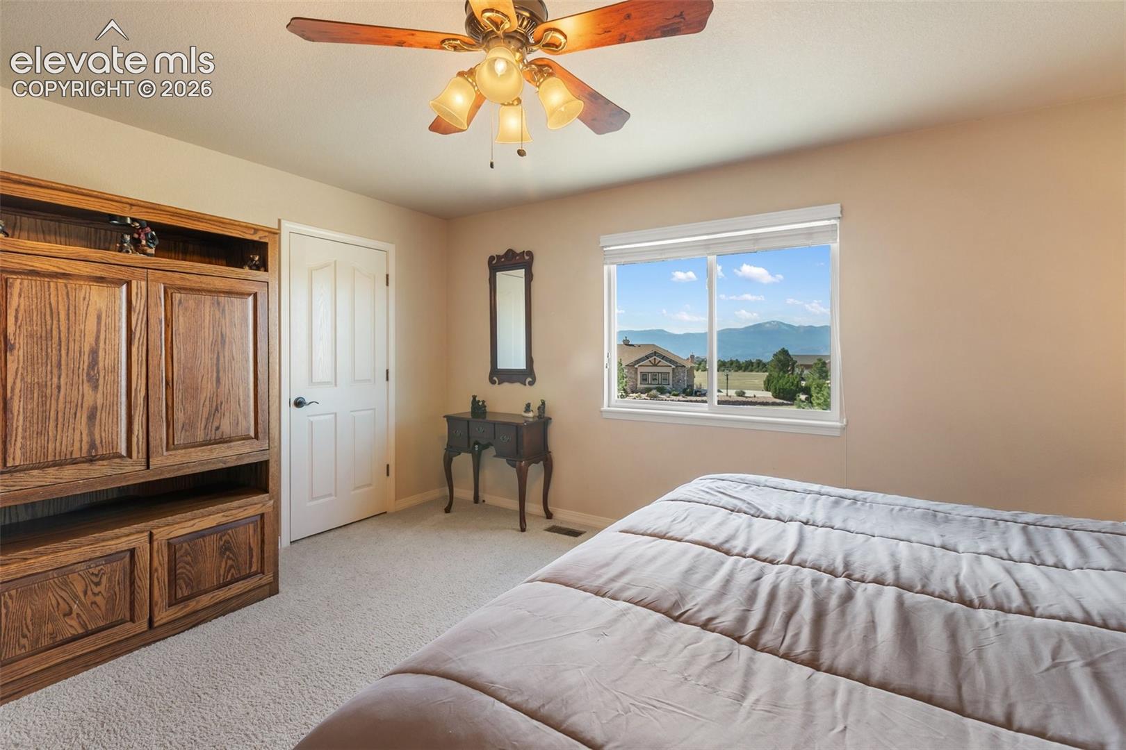Built-in wood cabinetry, ceiling fan with integrated lighting, wall-to-wall carpeting, and a window framing mountain scenery