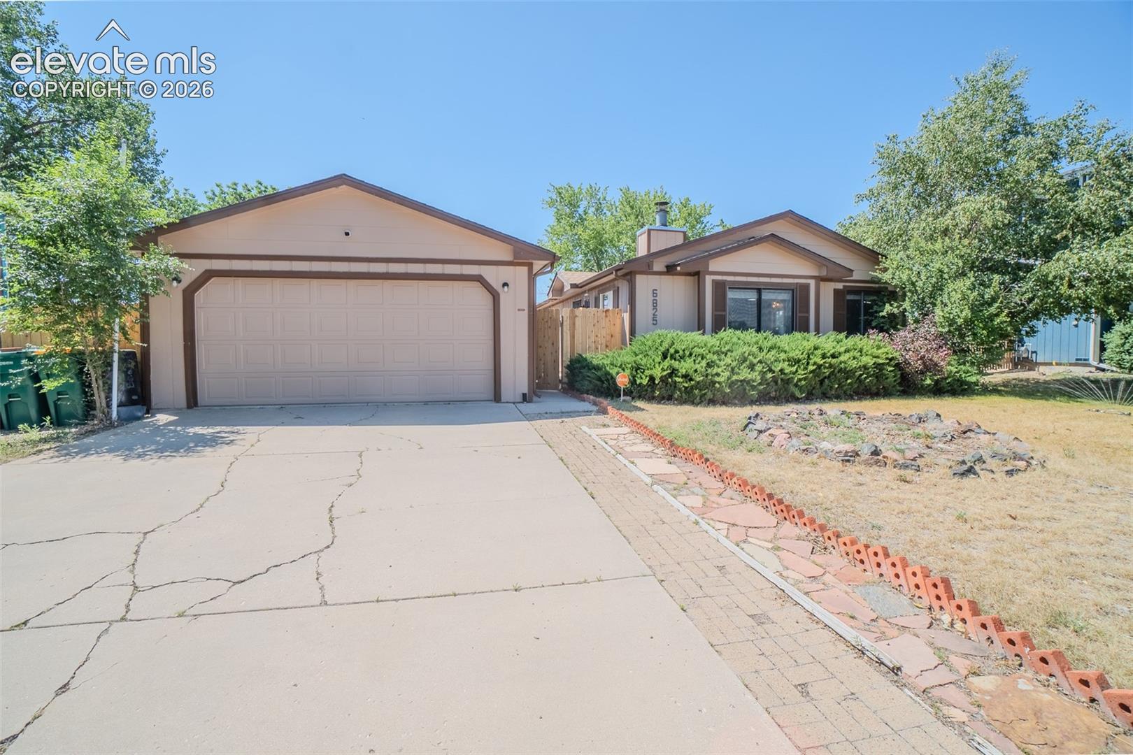 Ranch-style residence featuring an attached two-car garage, a concrete driveway, and a flagstone-style pathway