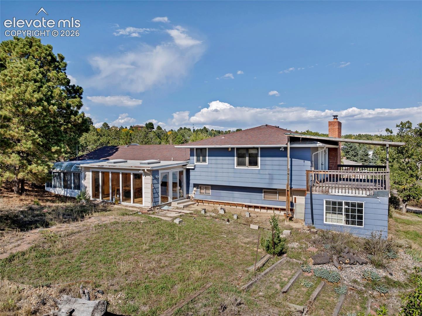 Expansive property featuring a multi-level structure, a large sunroom with multiple skylights, and a spacious outdoor deck