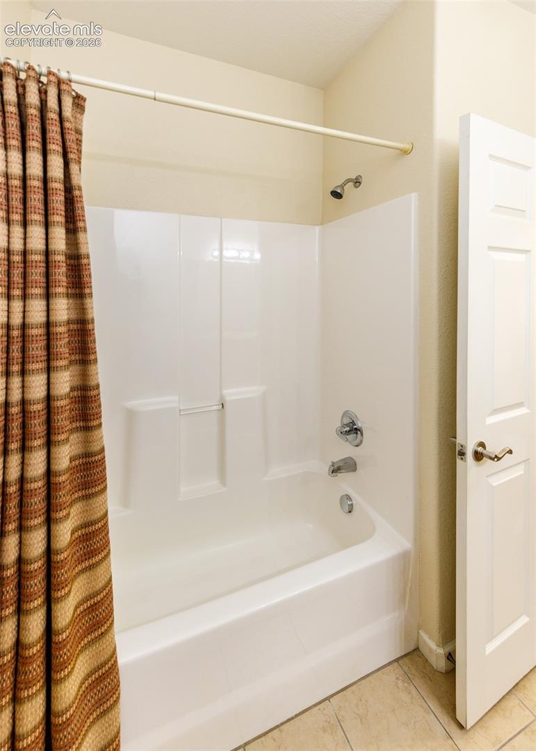 White acrylic tub and shower surround, chrome plumbing fixtures, and a six-panel interior door
