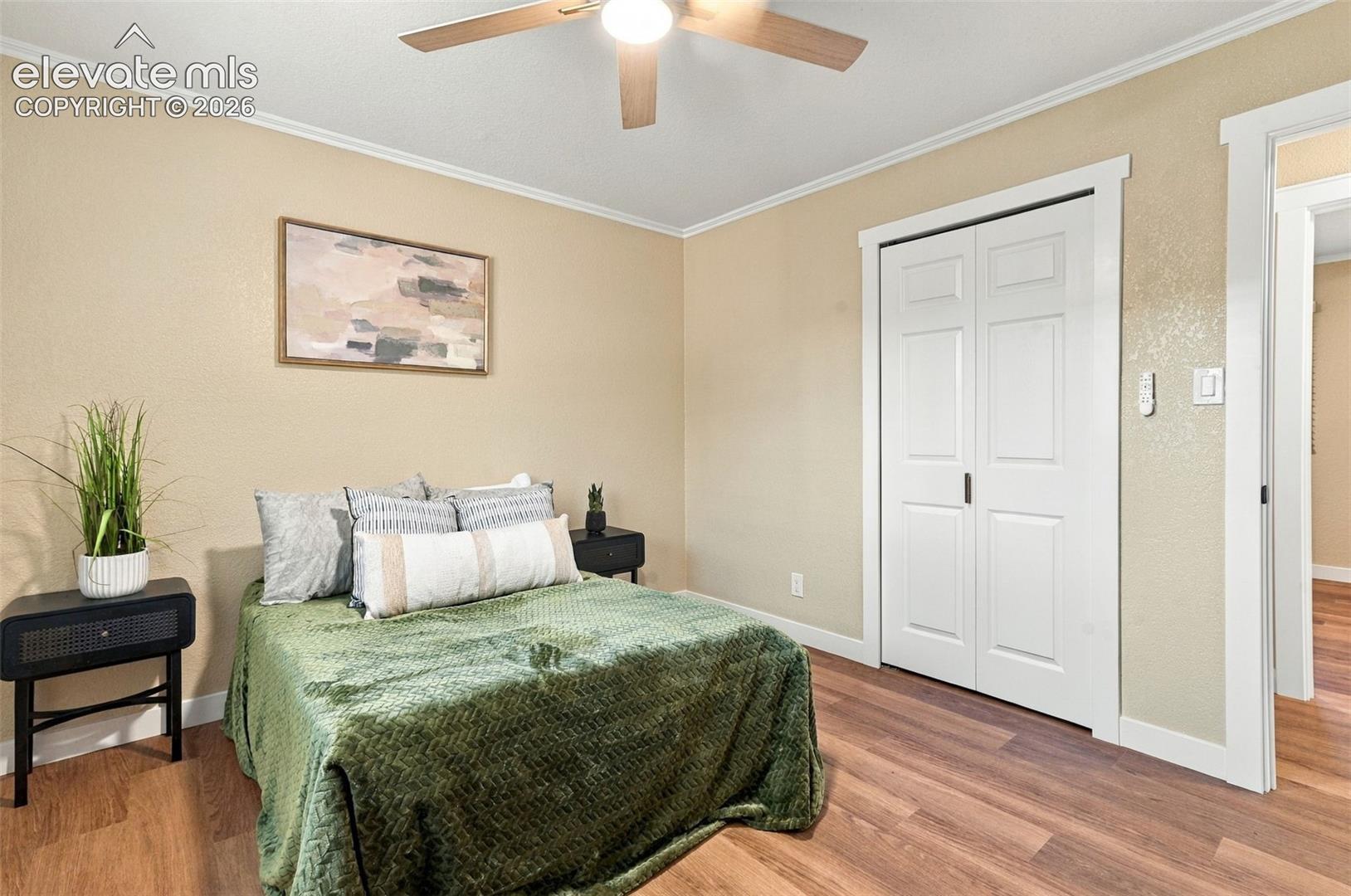 Wood-finish flooring, white double-panel closet doors, and a ceiling fan with integrated lighting
