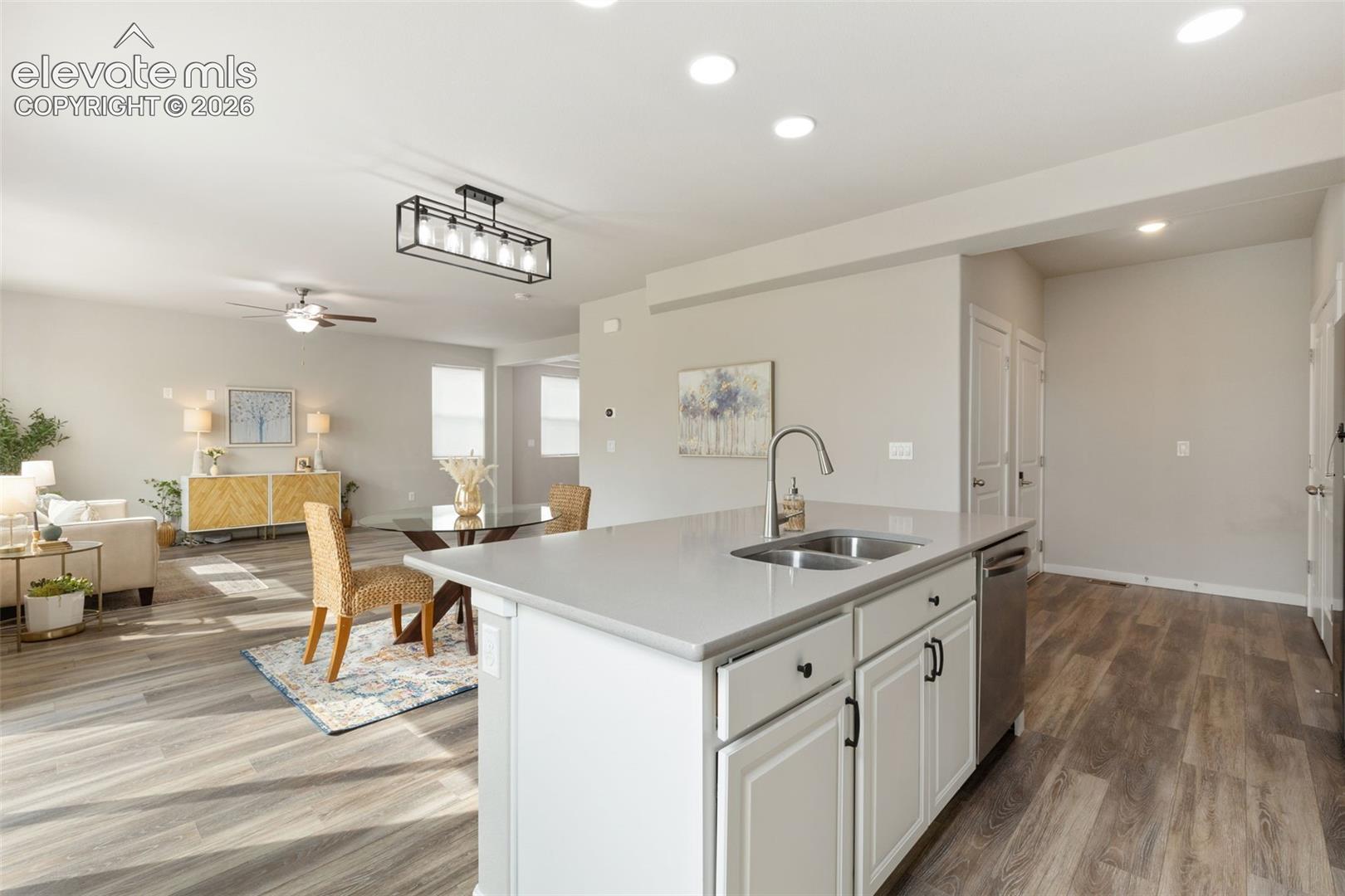 Kitchen island featuring a dual-basin stainless steel sink with a high-arc faucet, integrated dishwasher, and white cabinetry