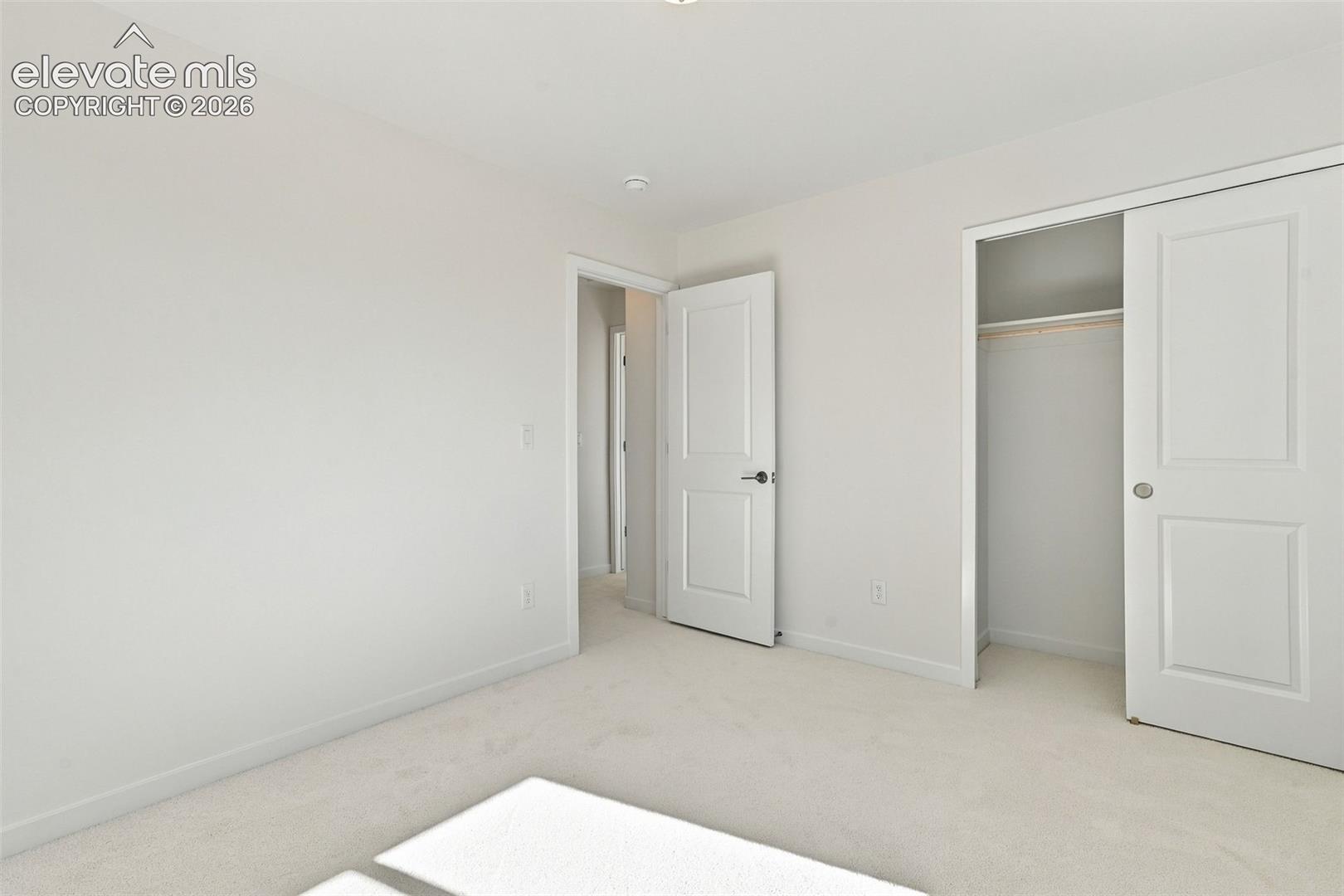 Neutral carpet flooring, white walls, white trim, recessed lighting, and a closet with sliding doors
