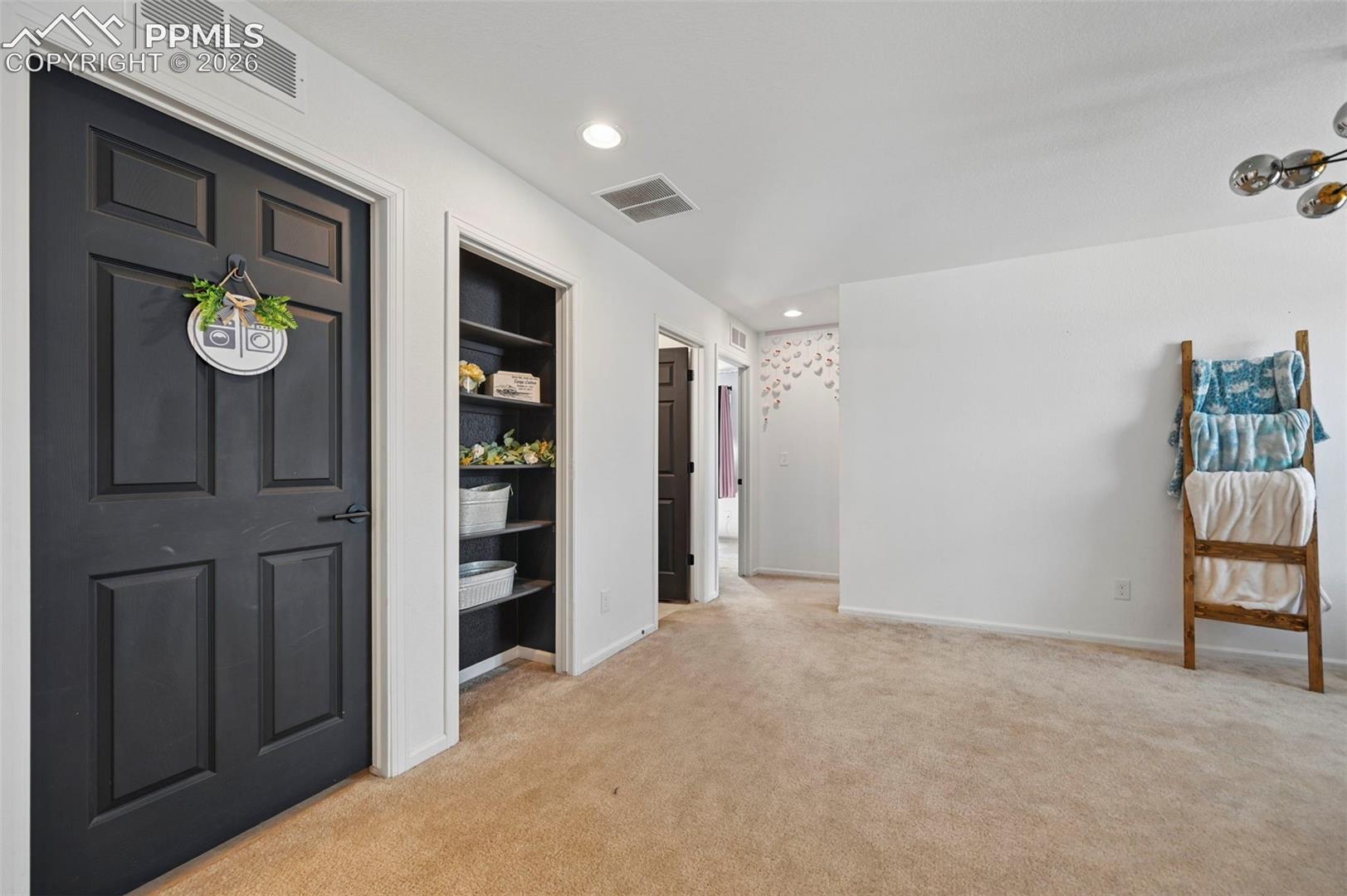 Interior space featuring textured carpeting, white walls, and a built-in shelving unit