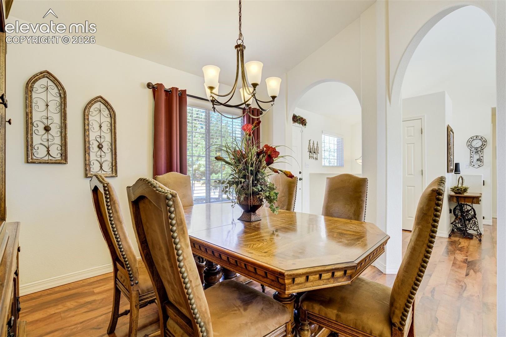 Architectural arched entryways, wood-finish flooring, and a multi-light chandelier fixture