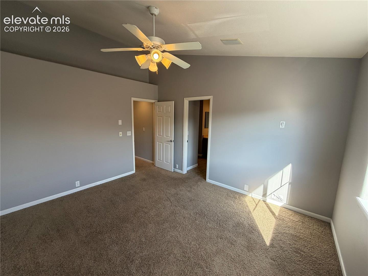 Vaulted ceiling with a ceiling fan, plush carpeting, and light gray walls