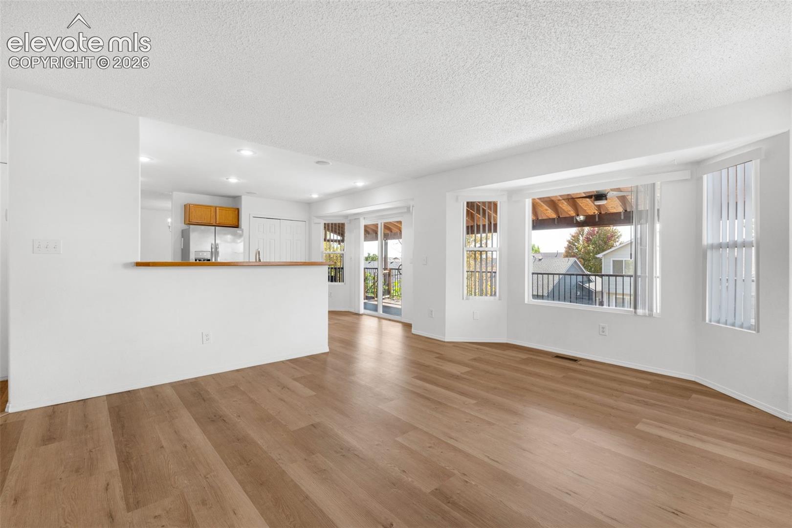 Wood-finish flooring, recessed lighting, bay windows, and a sliding glass door providing outdoor access