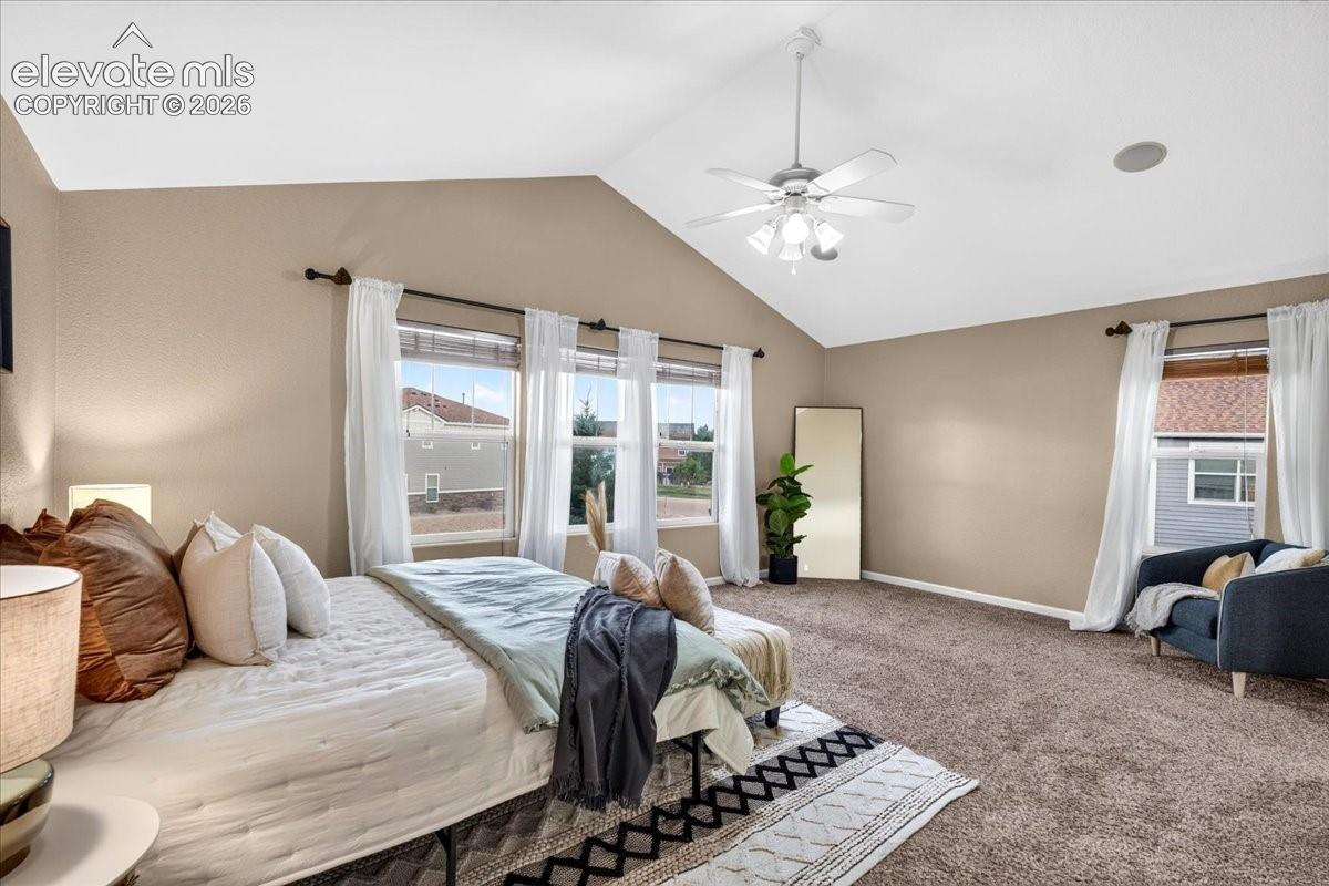 Vaulted ceiling with an attached ceiling fan, recessed ceiling speaker, carpeted flooring, and multiple windows