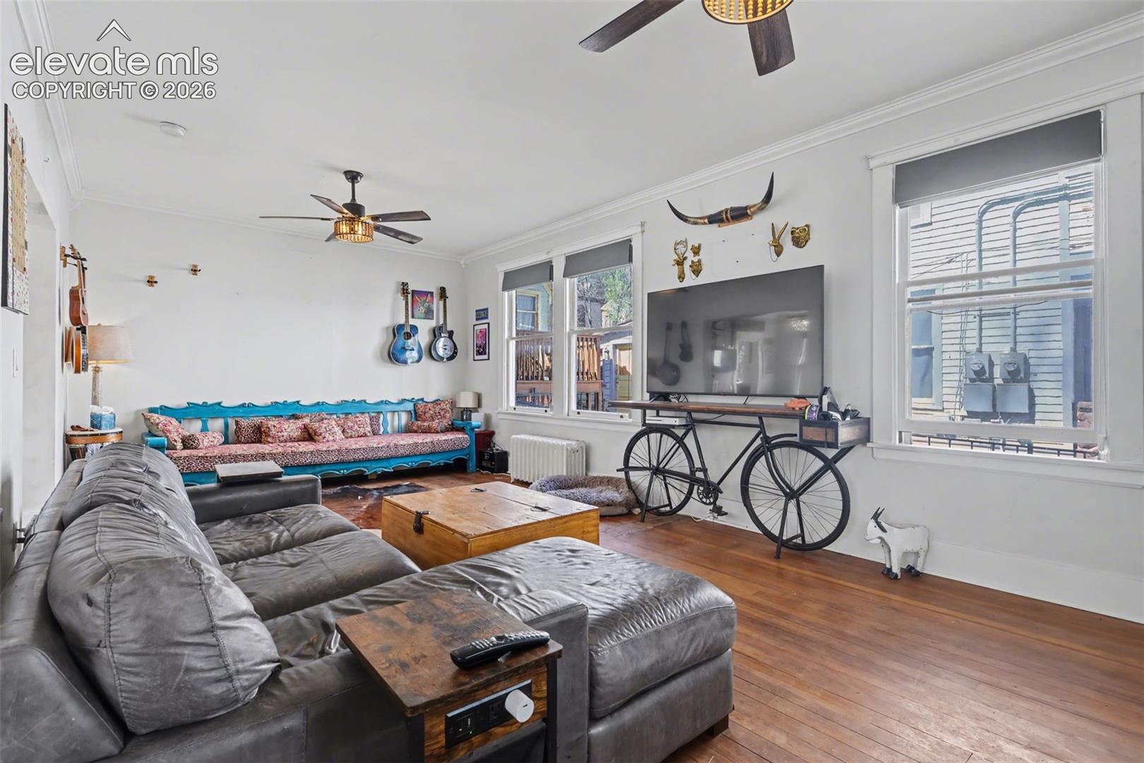 Living / Dining area with ceiling fan, crown molding, hardwood, and large windows for natural lighting