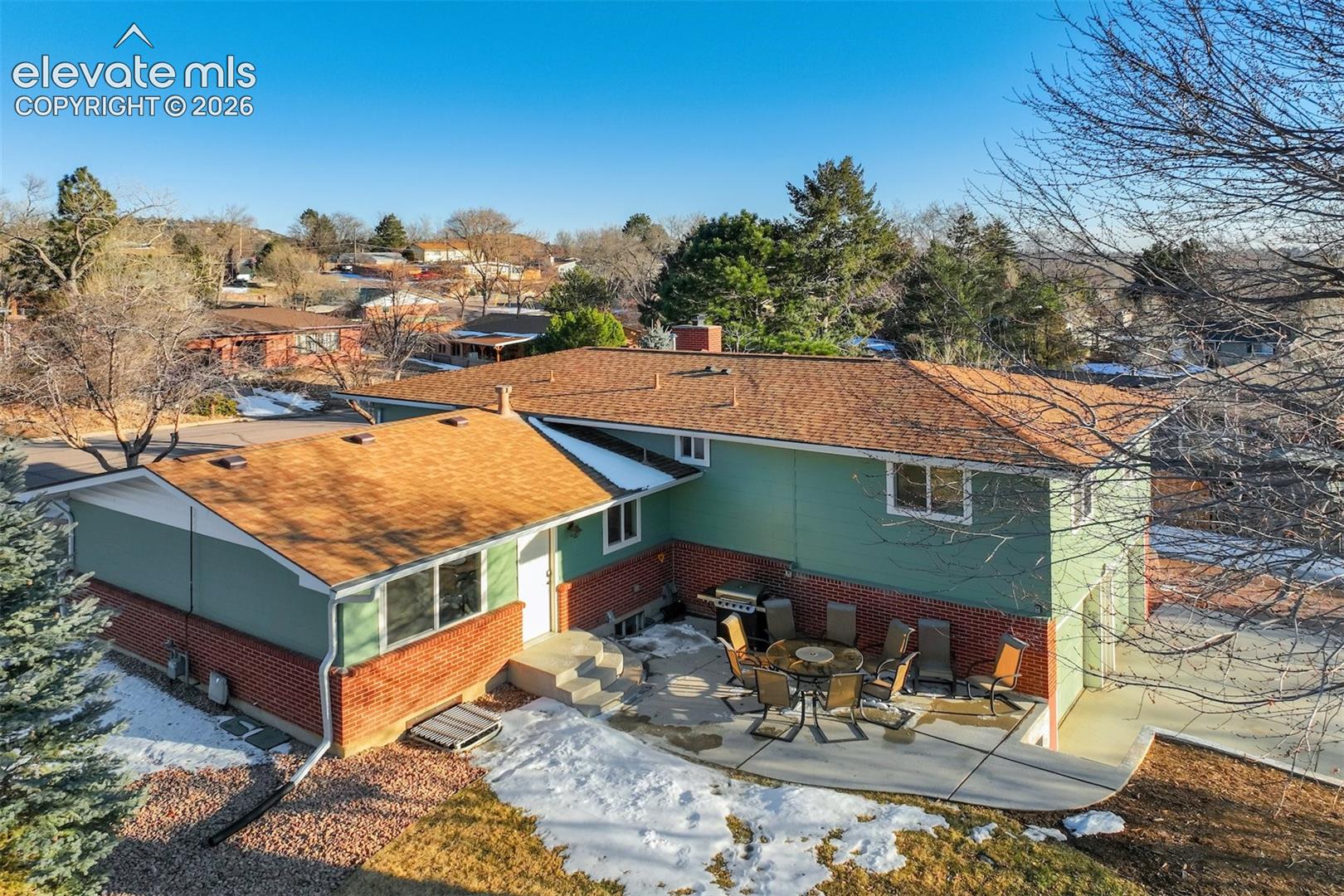Two-story exterior with brick and siding facade, featuring a patio area, multiple windows, and a shingle roof