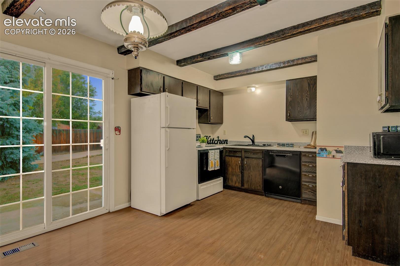 Kitchen featuring woodbeams and walk out to large backyard 
