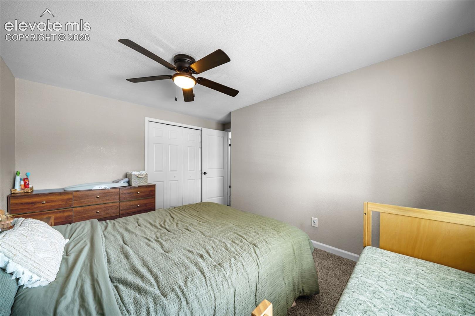 Spacious bedroom featuring neutral wall finishes, carpeted flooring, and a ceiling fan with integrated lighting