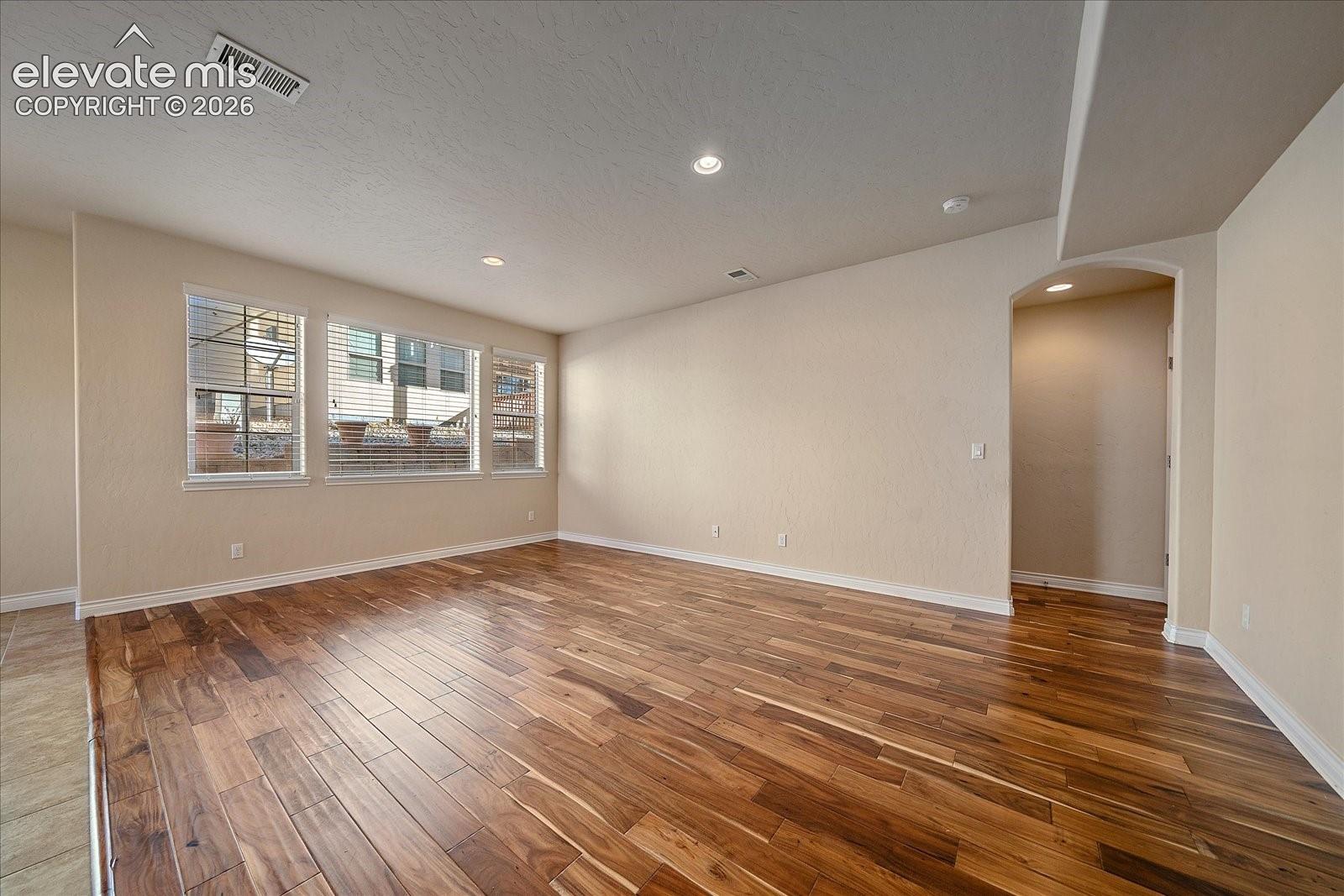Room featuring wood-finish flooring, recessed lighting, and multiple windows with exterior masonry detail