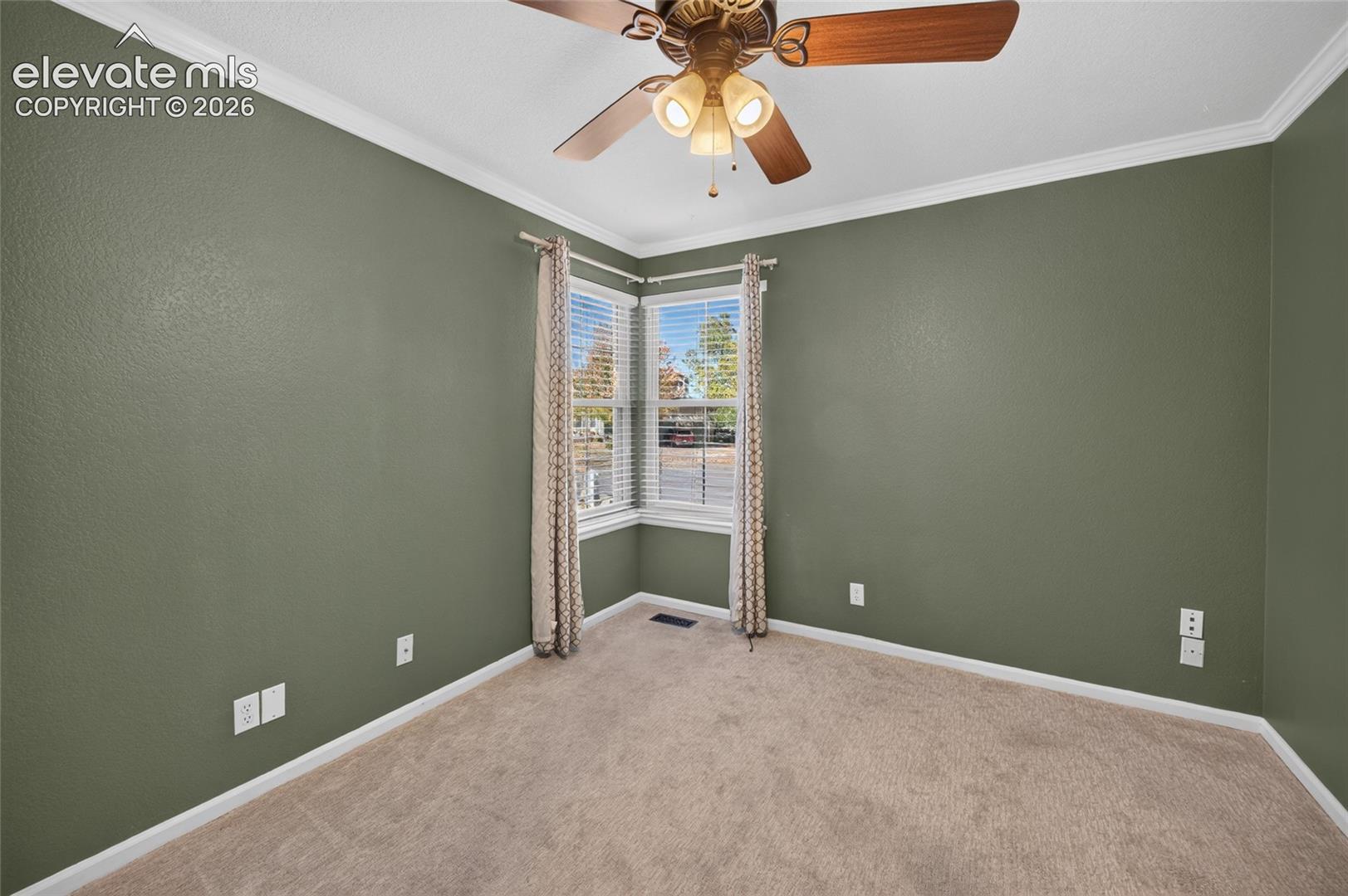 Room featuring carpeted flooring, corner windows, neutral-toned walls, and a ceiling-mounted fan with integrated lighting