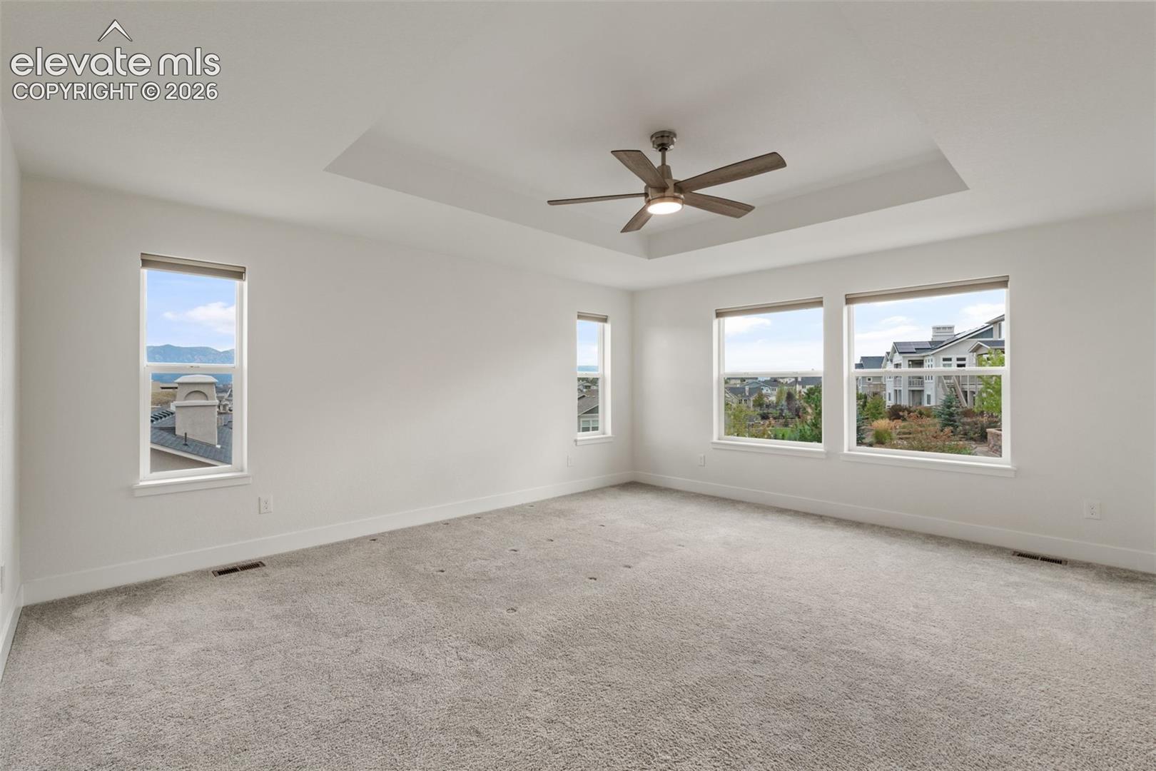Recessed ceiling with a central fan, light gray carpeting, and mountain views