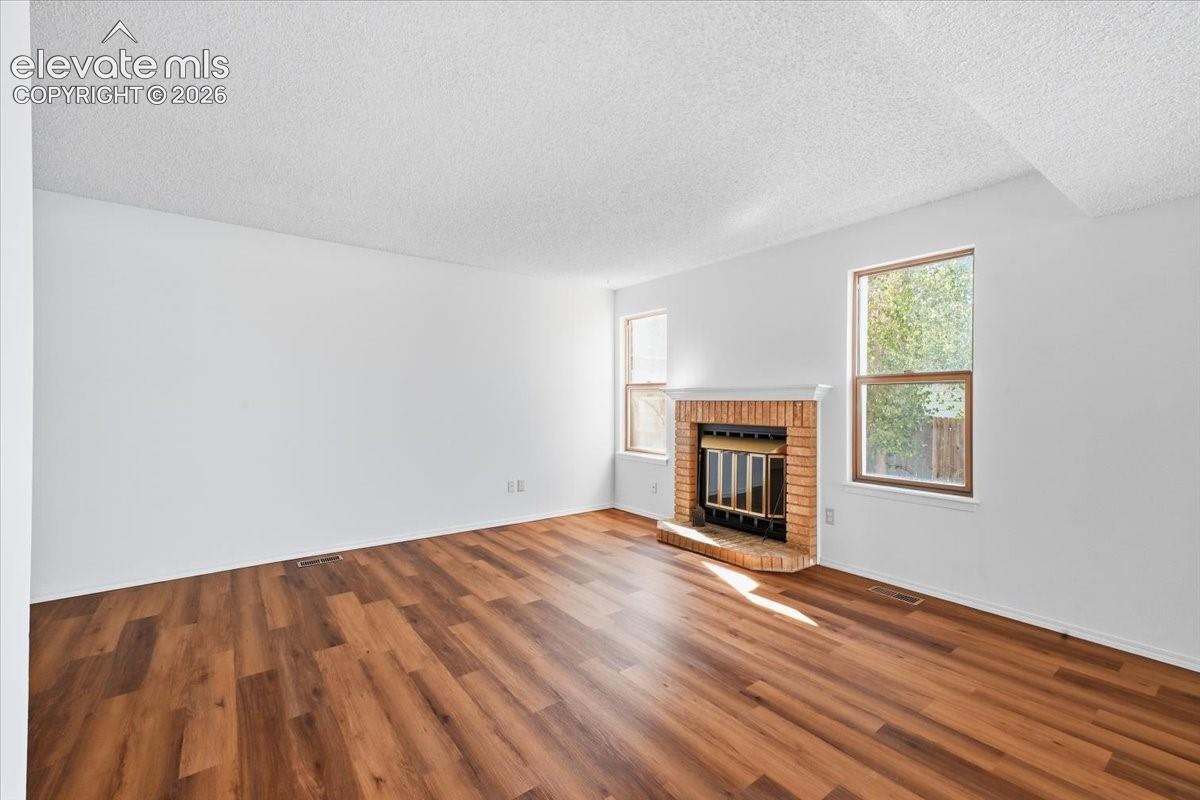Living room with a wood-burning fireplace and new LVP flooring at , Colorado Springs, CO.