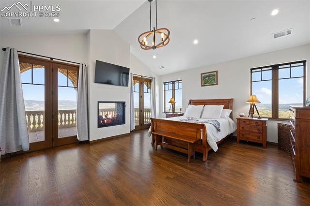 Main-floor primary suite with vaulted ceilings, see-through gas fireplace, balcony access, and mountain views.