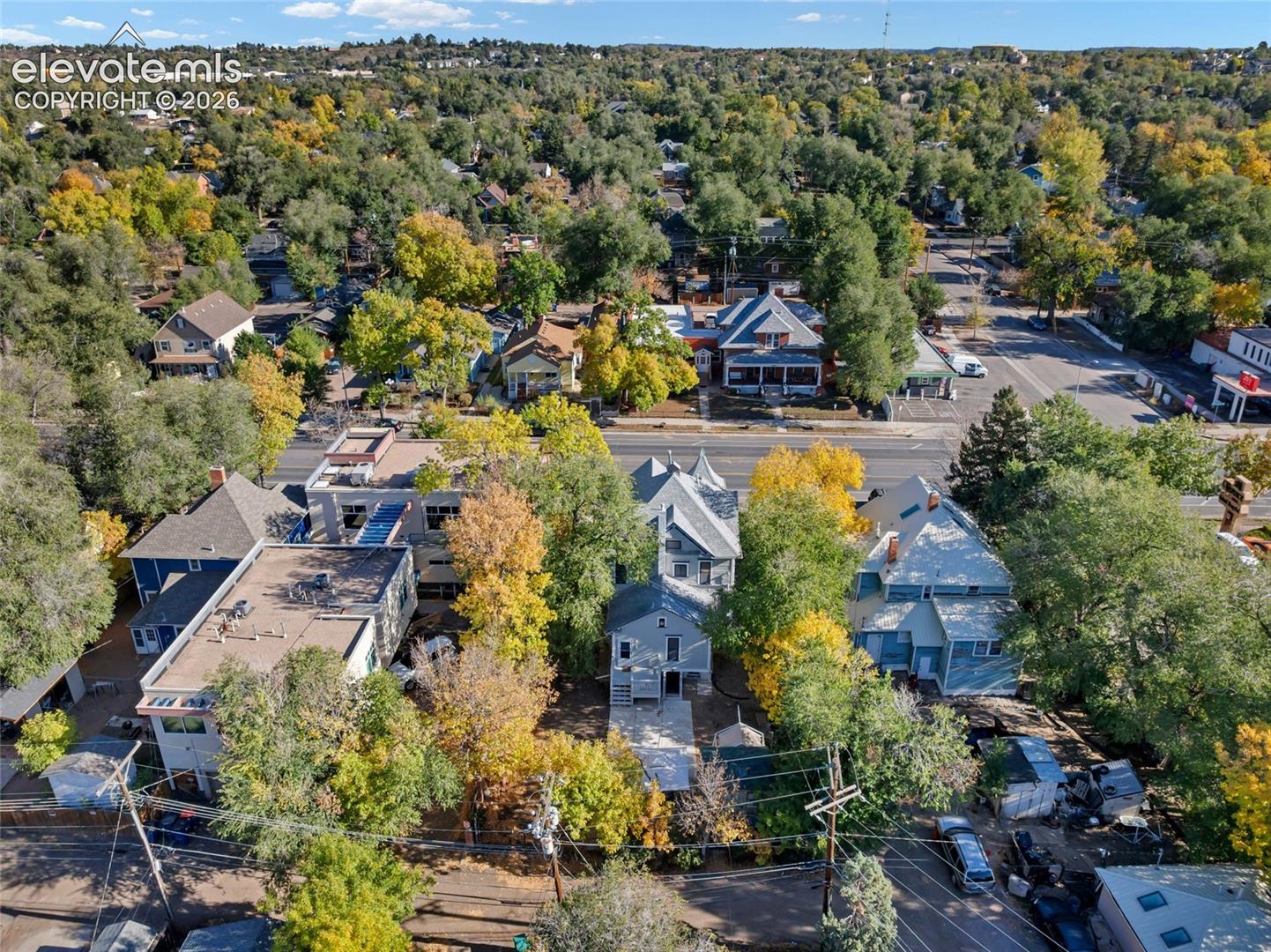 Aerial view of the property featuring a multi-level structure, a concrete driveway, and dense mature canopy coverage
