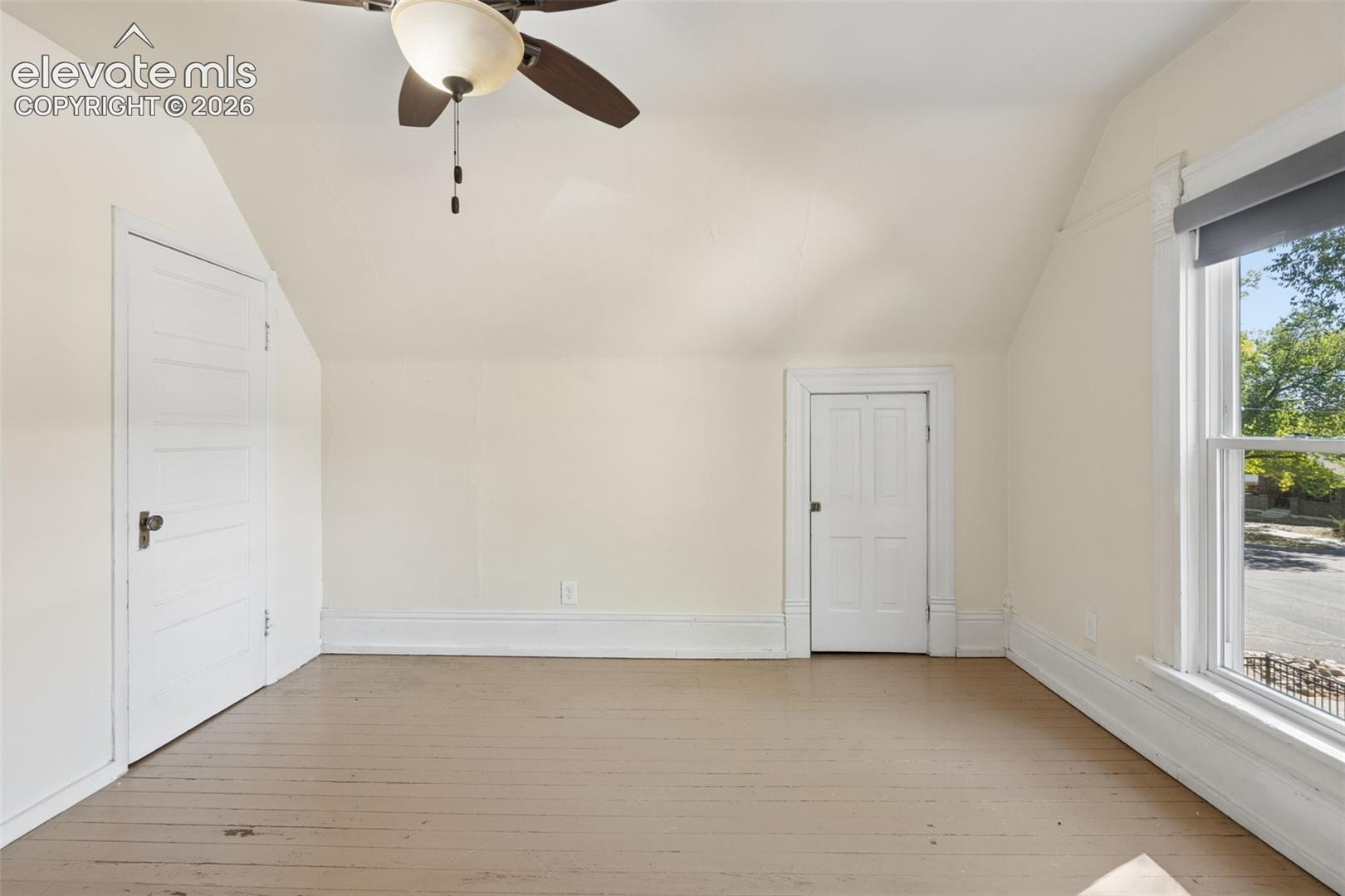 Bedroom #2 featuring vaulted ceilings, painted wood flooring, a ceiling fan with integrated lighting