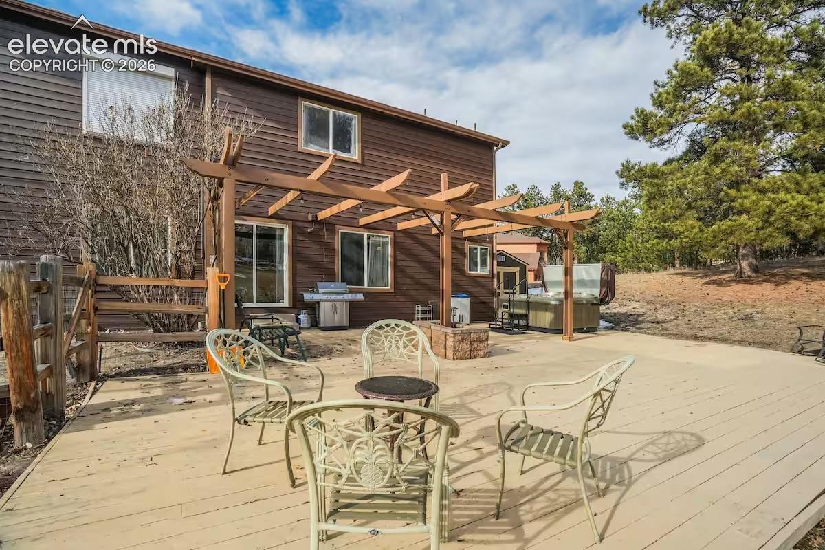 Expansive exterior deck featuring a pergola, wood-finish siding, and multiple windows