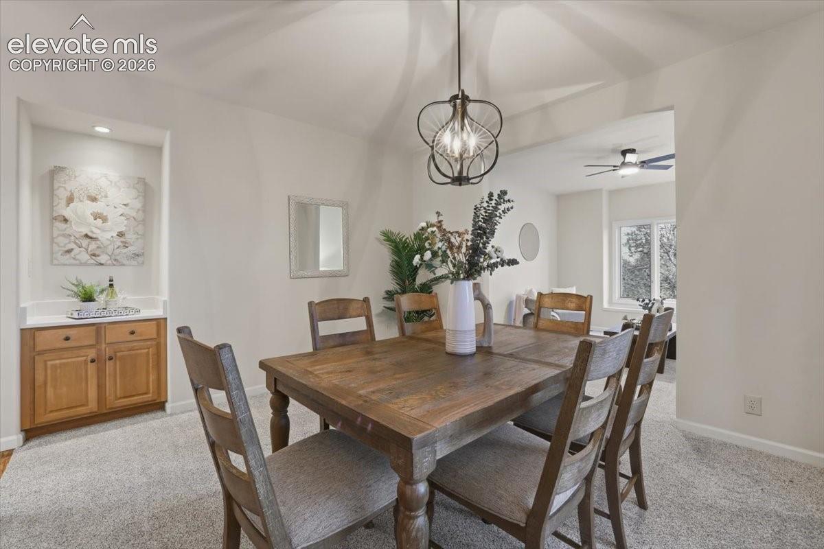 Recessed wall niche with accent lighting and built-in wood cabinetry, overhead decorative light fixture, and light-toned carpeting
