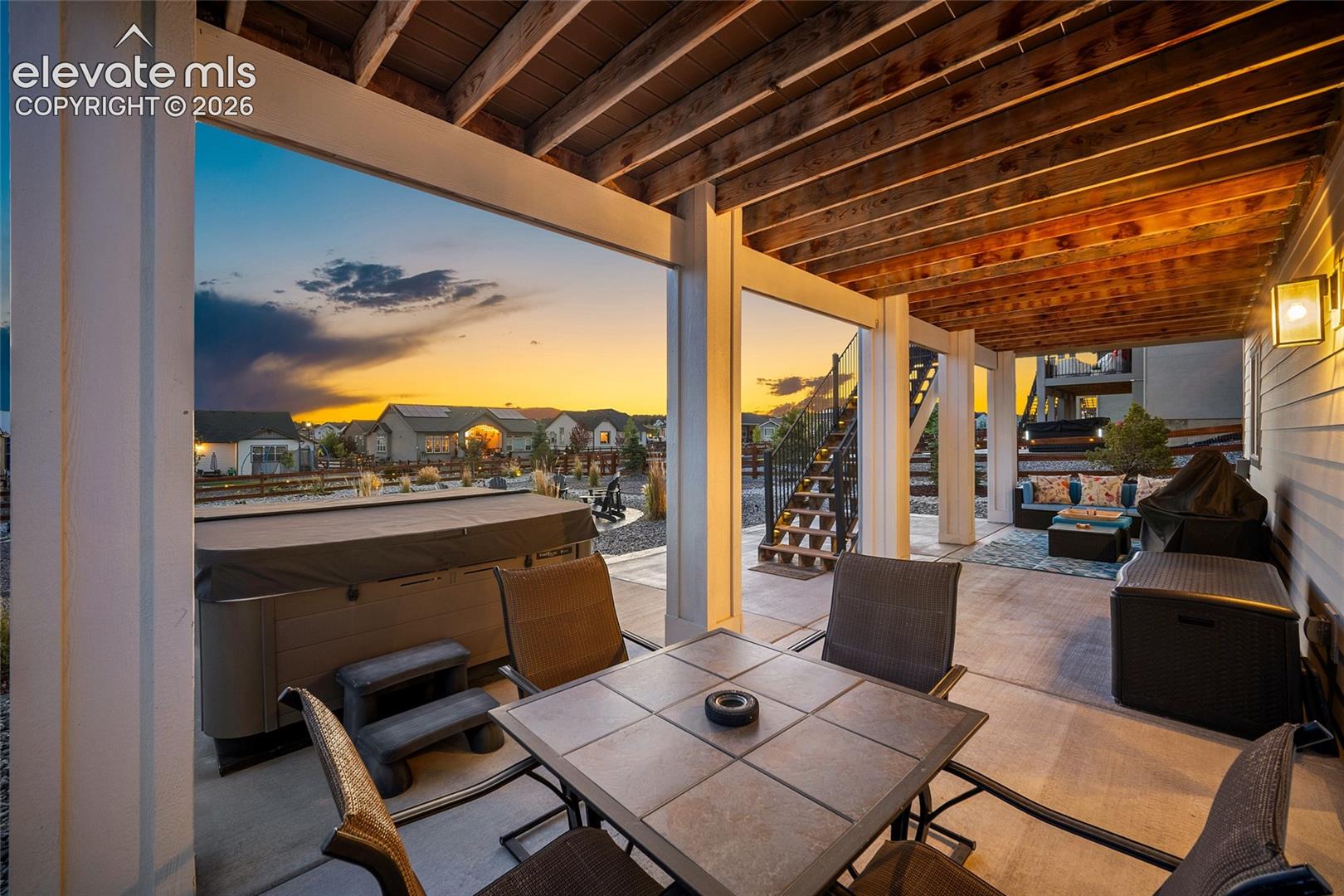 Covered patio featuring exposed wood beam ceiling, concrete flooring, and exterior lighting