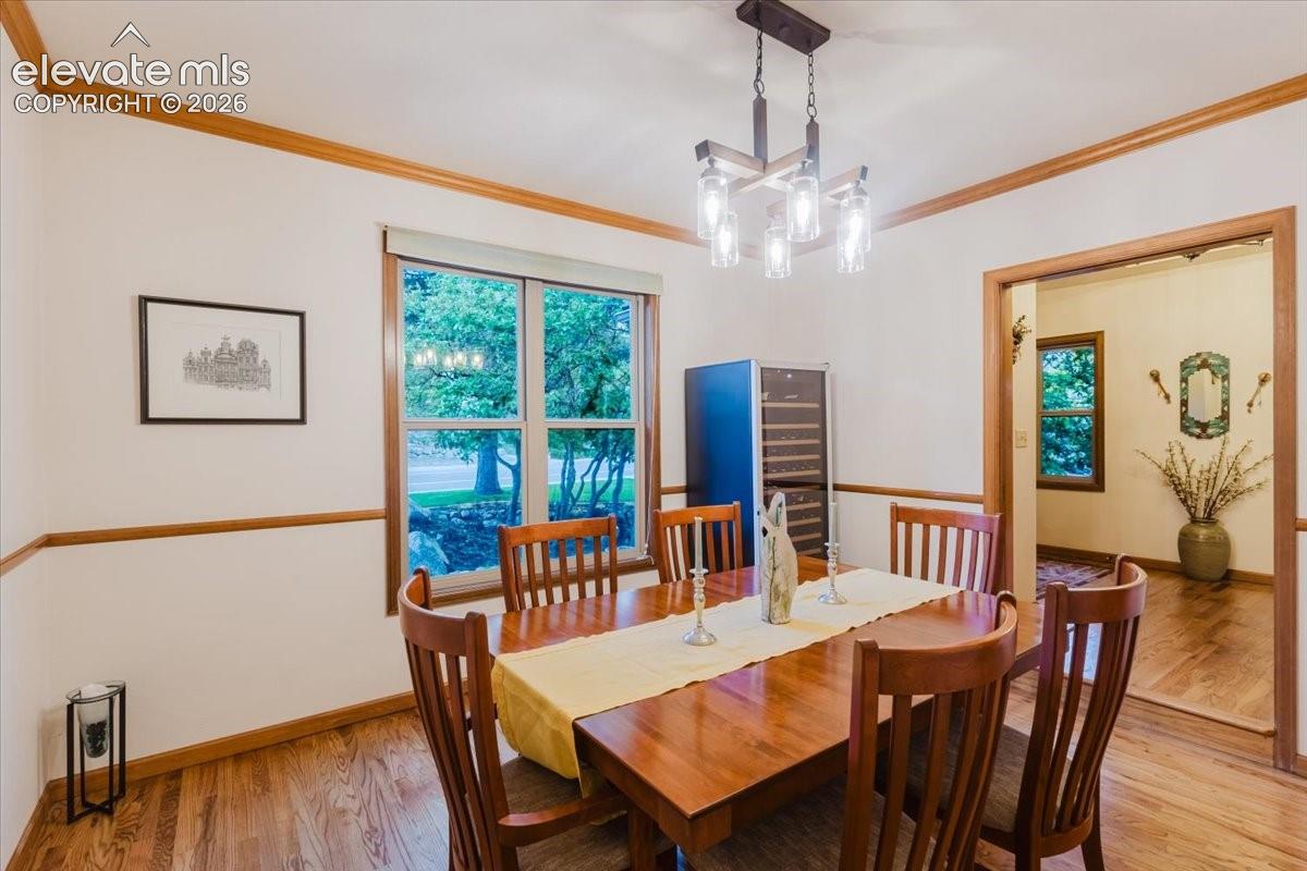 Dining area with hard wood flooring, a contemporary chandelier, and a large window