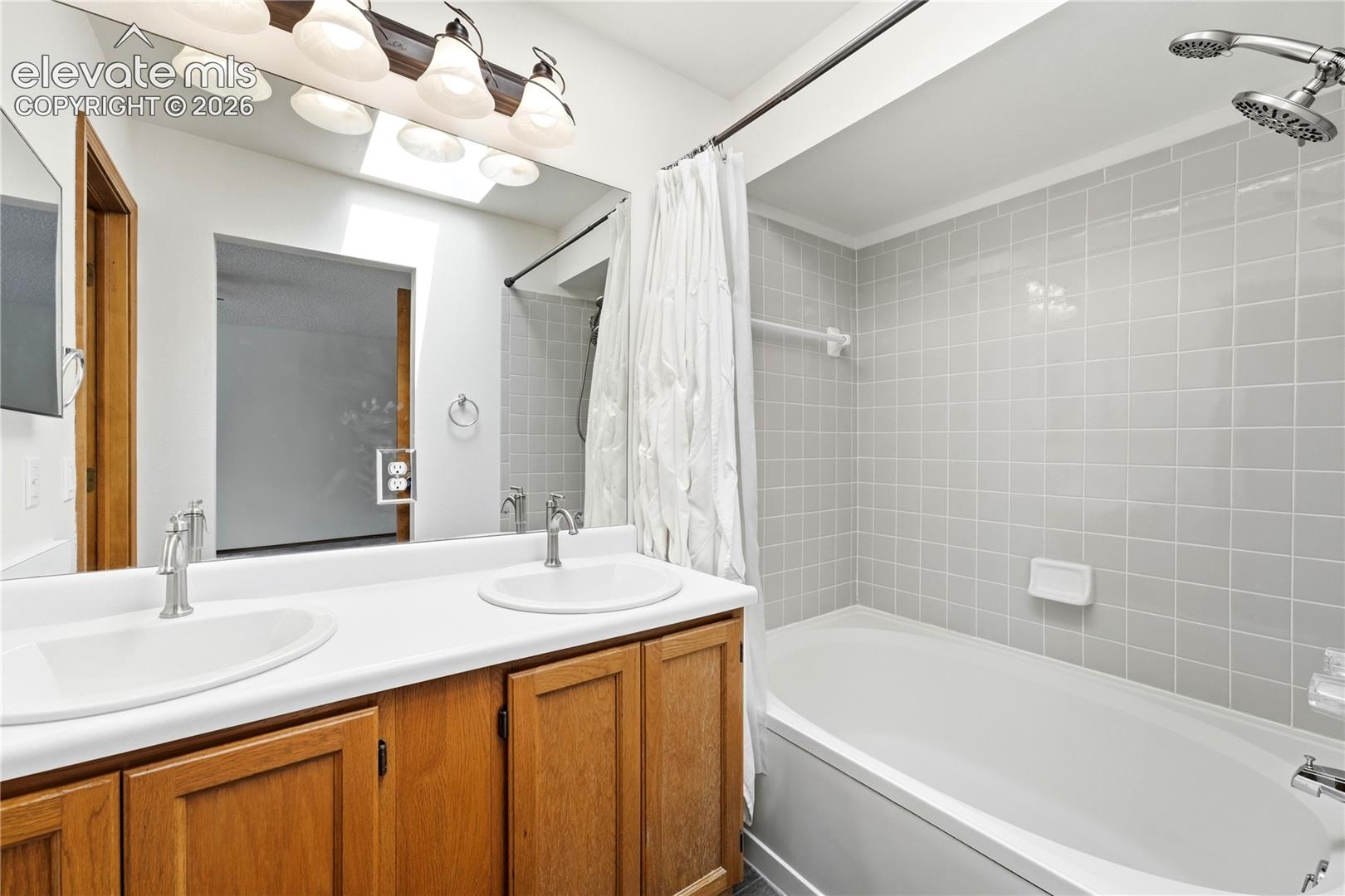 Double vanity with integrated sinks, a full-width mirror, and a skylight