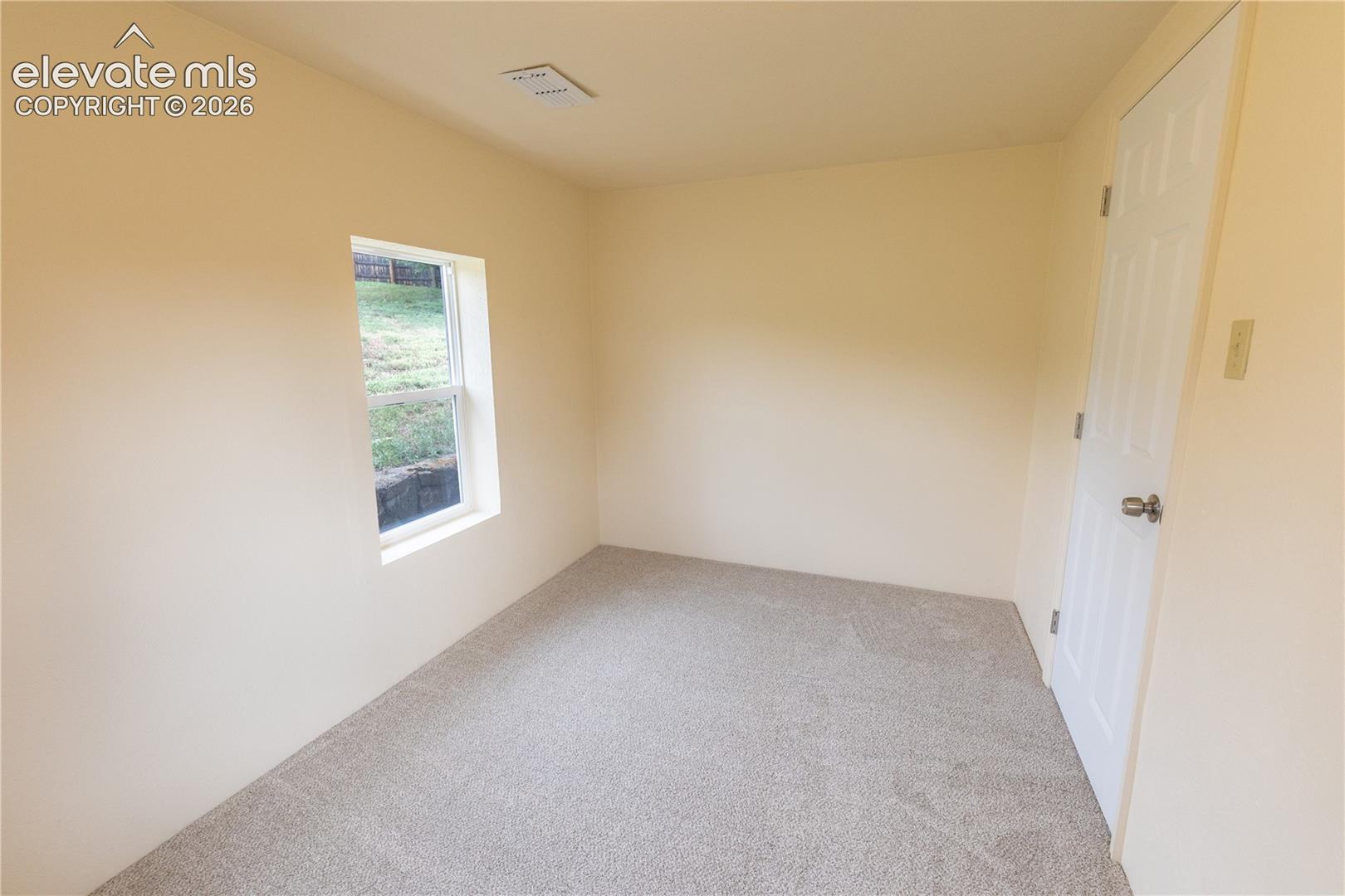 Interior room featuring neutral wall paint, carpeted flooring, a single-panel window, and a multi-panel door