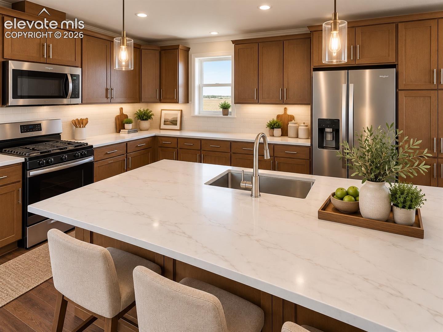 Kitchen – Close-up kitchen view showcases an oversized island with sink and expansive work surface, warm cabinetry, stainless steel appliances, pendant lighting, and plentiful storage.