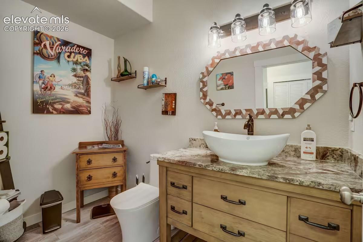 Vanity with a vessel sink, stone countertop, and wood-finish cabinetry