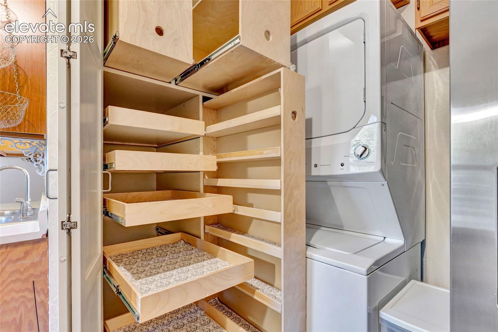 Built-in wood cabinetry featuring pull-out storage drawers and shelving, paired with a stackable laundry appliance