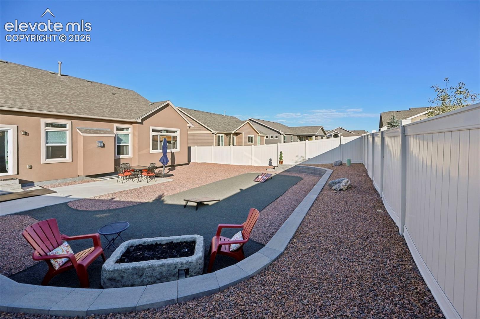 Expansive backyard featuring a built-in fire pit, multiple hardscaped areas, and a full privacy fence