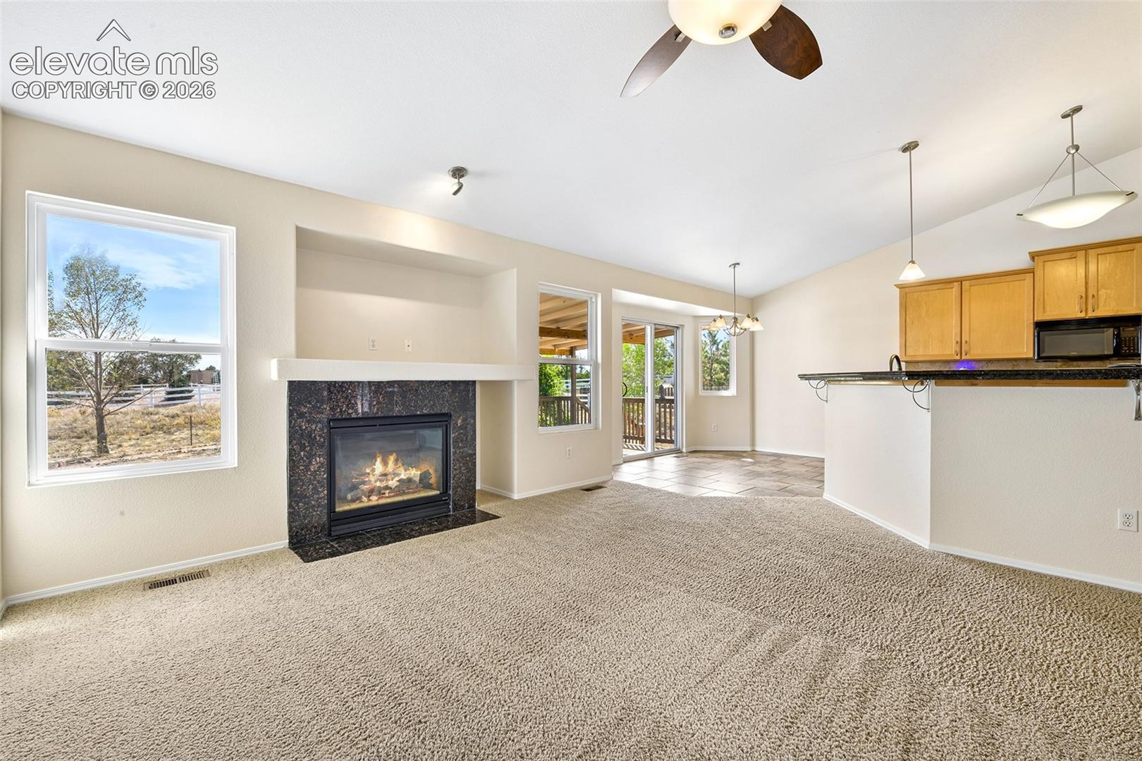 Living area featuring a fireplace with a dark stone surround, a ceiling fan, and recessed shelving