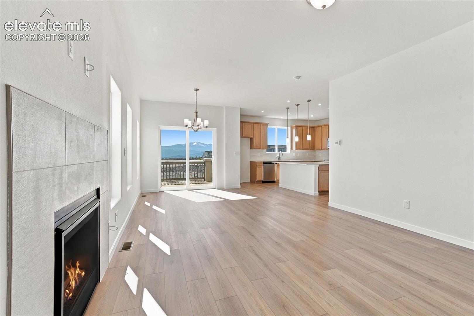 Open-concept living space featuring wood-finish flooring, a tiled fireplace, and a sliding glass door to an outdoor area
