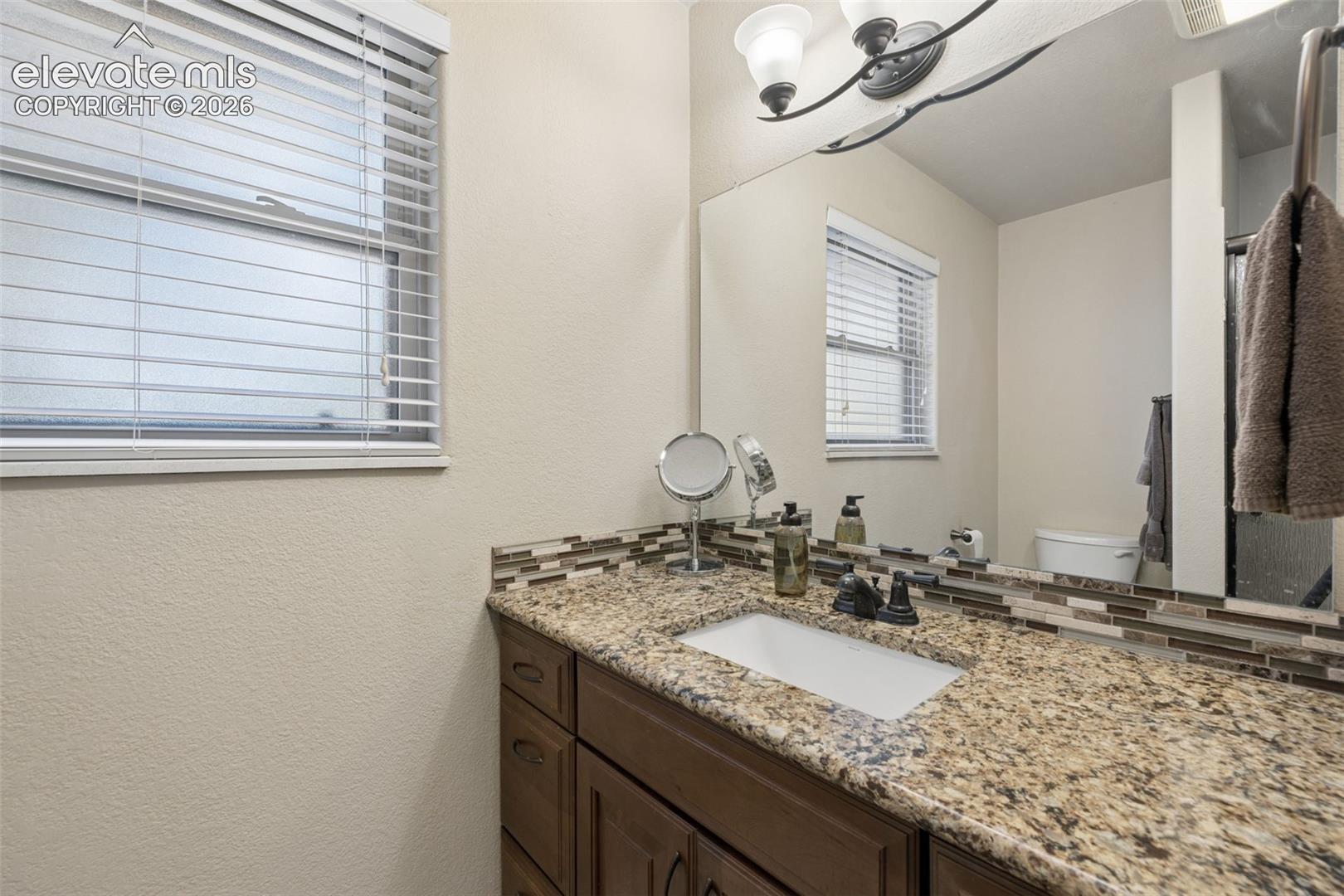 Primary 3/4 bathroom with granite countertop and walk-in shower