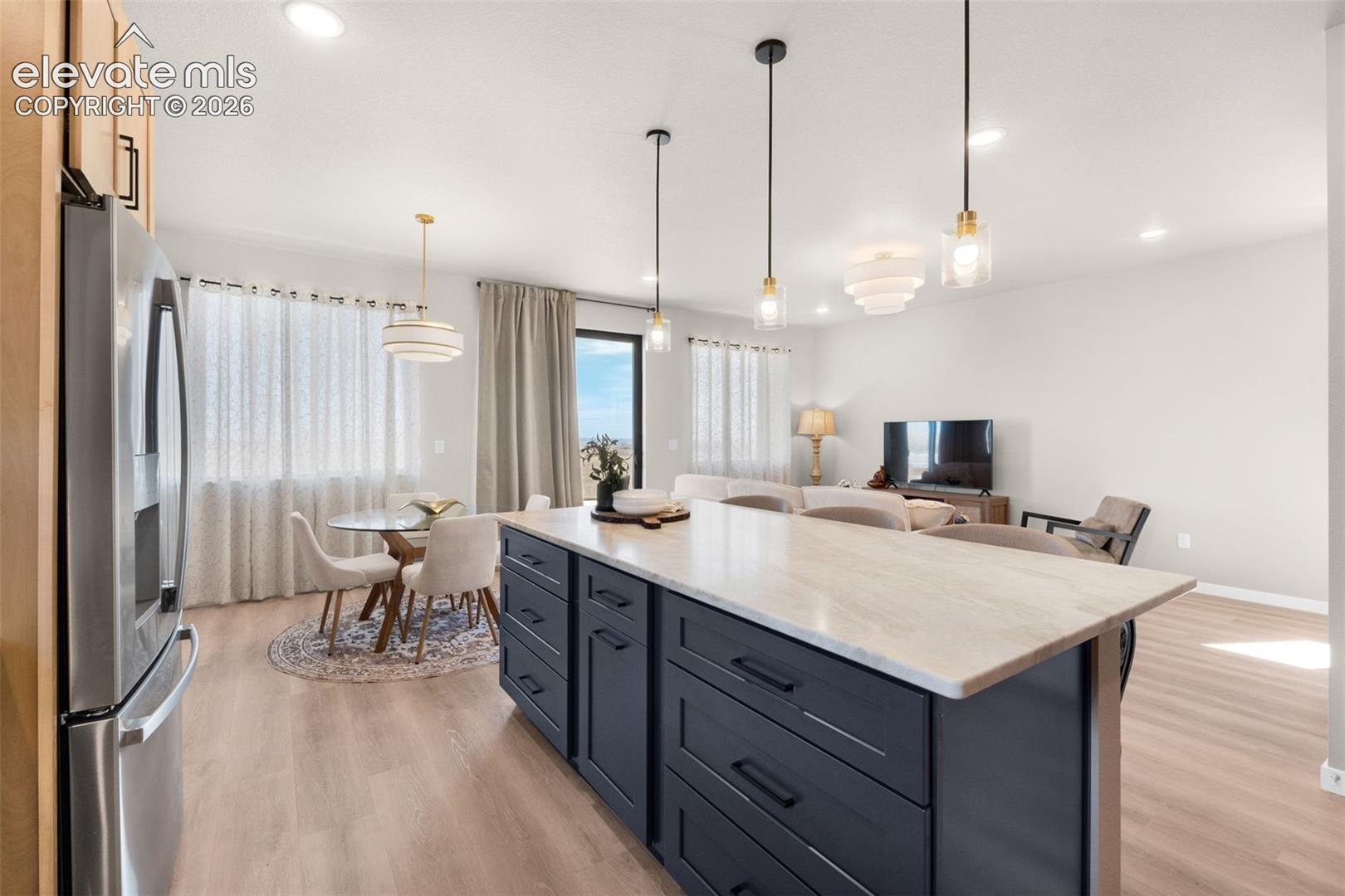 Contemporary kitchen island with a light-toned countertop, dark-finish cabinetry, and recessed lighting