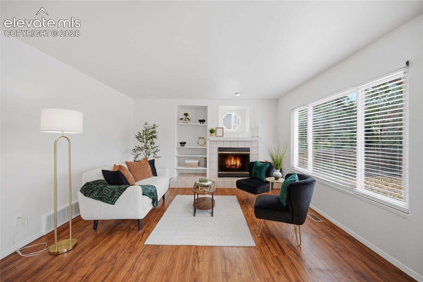 Fireplace with tile surround, built-in recessed shelving, and wood-finish flooring