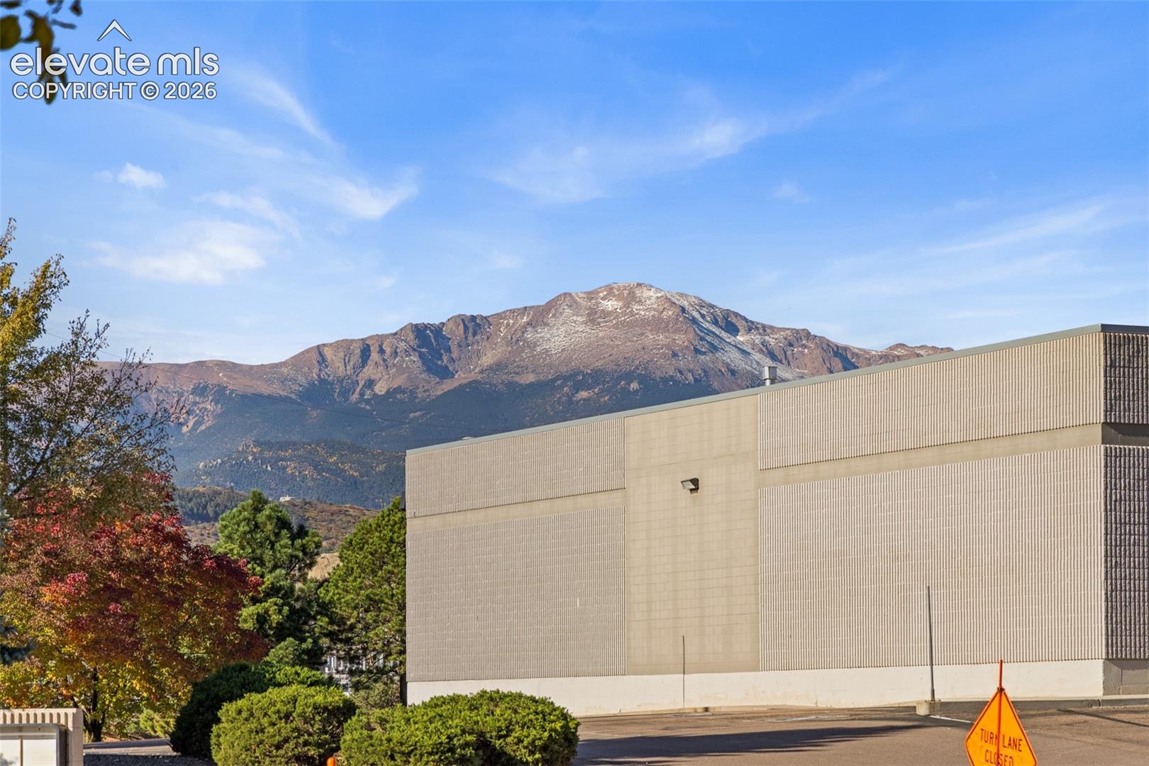 Exterior masonry structure with mature deciduous trees and a mountain range backdrop