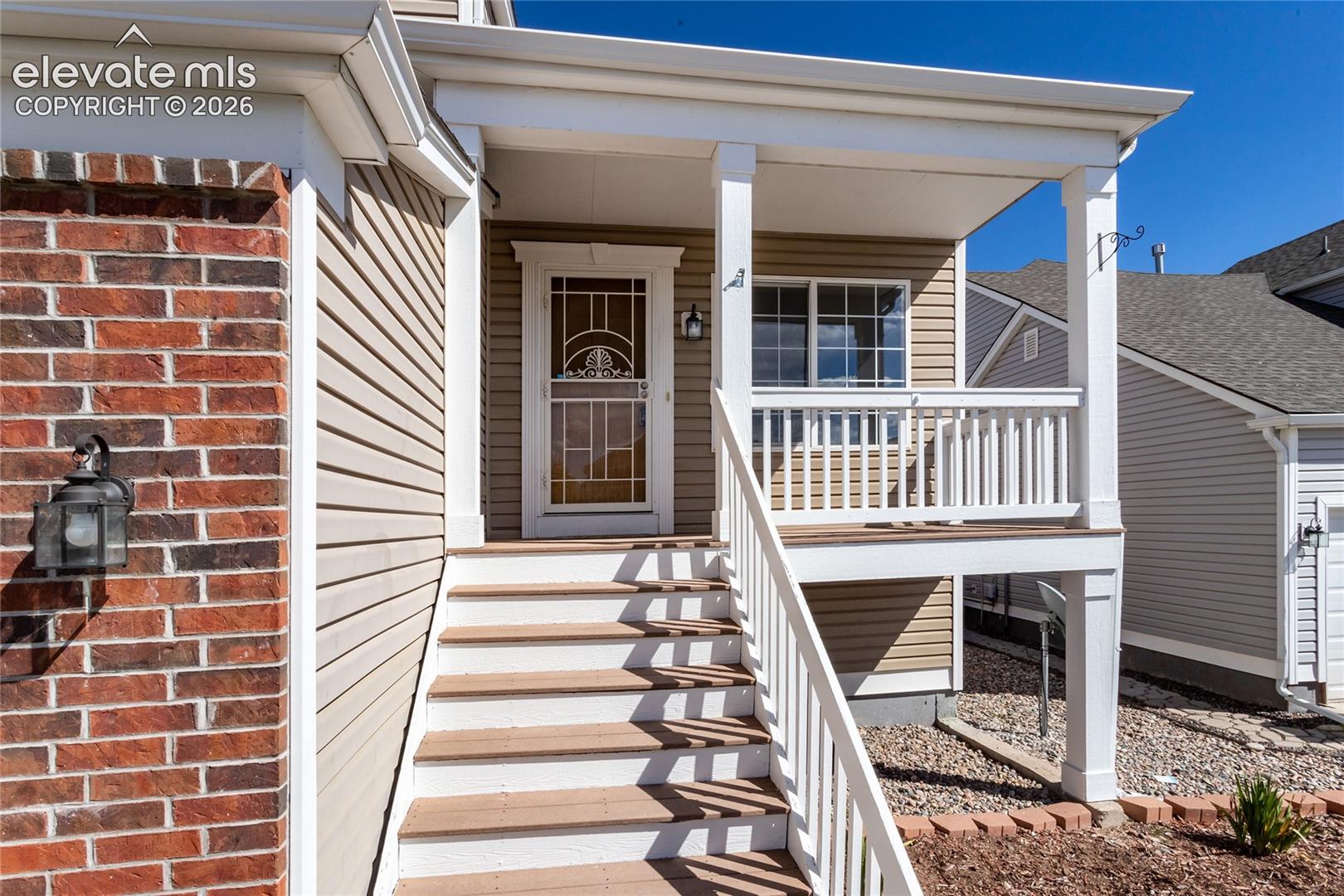 The welcoming porch steps lead up to a covered entry lit by an exterior wall lantern