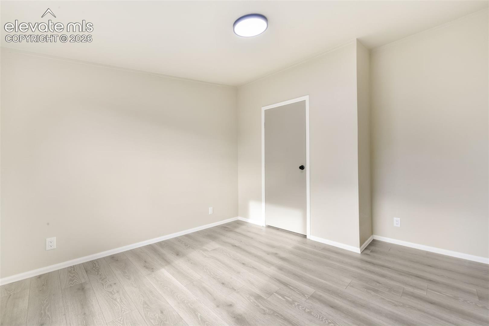 Light wood-finish flooring, neutral wall tones, and a flush-mount ceiling light