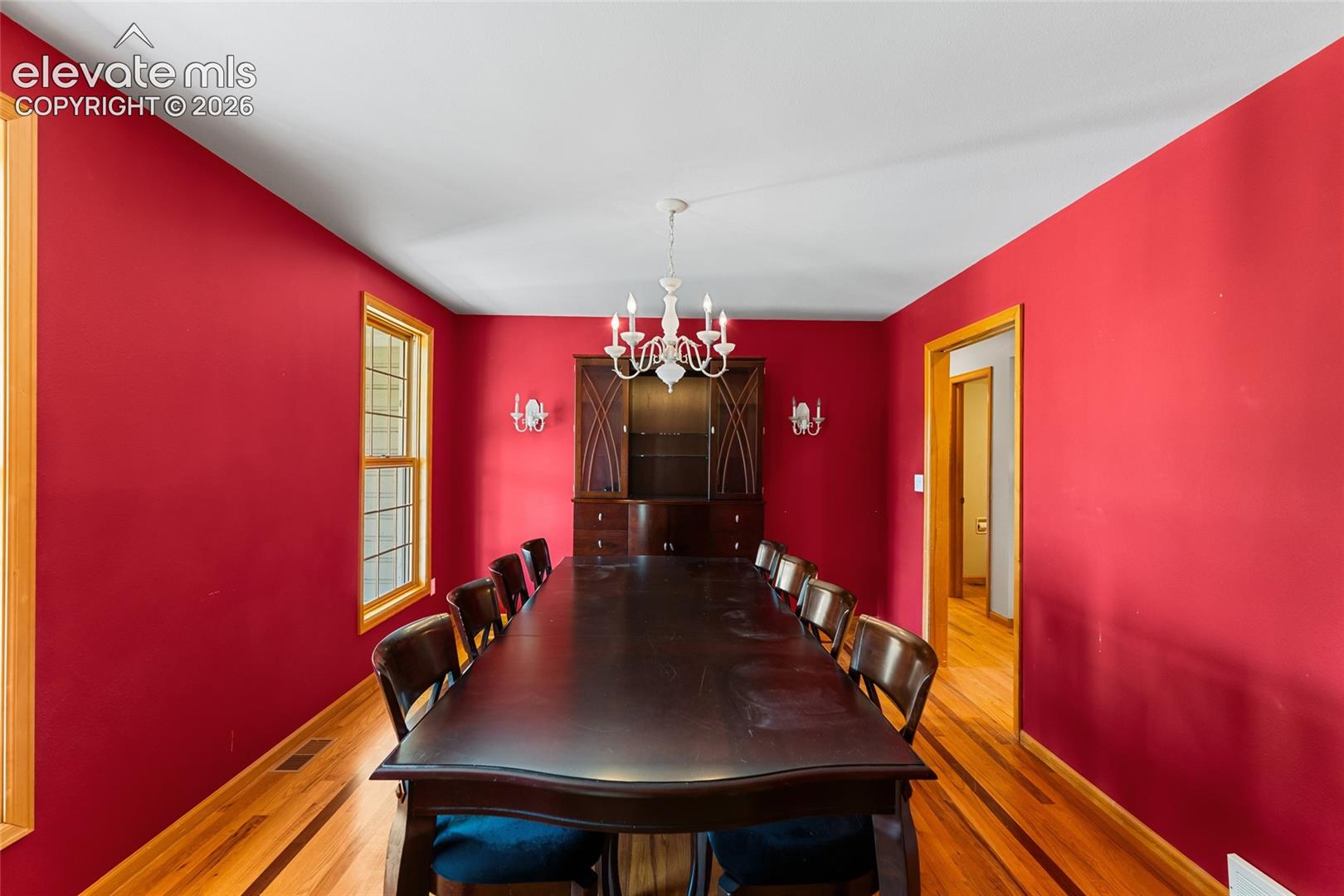 Hardwood flooring, wood trim, built-in display cabinetry, and a chandelier with wall sconces