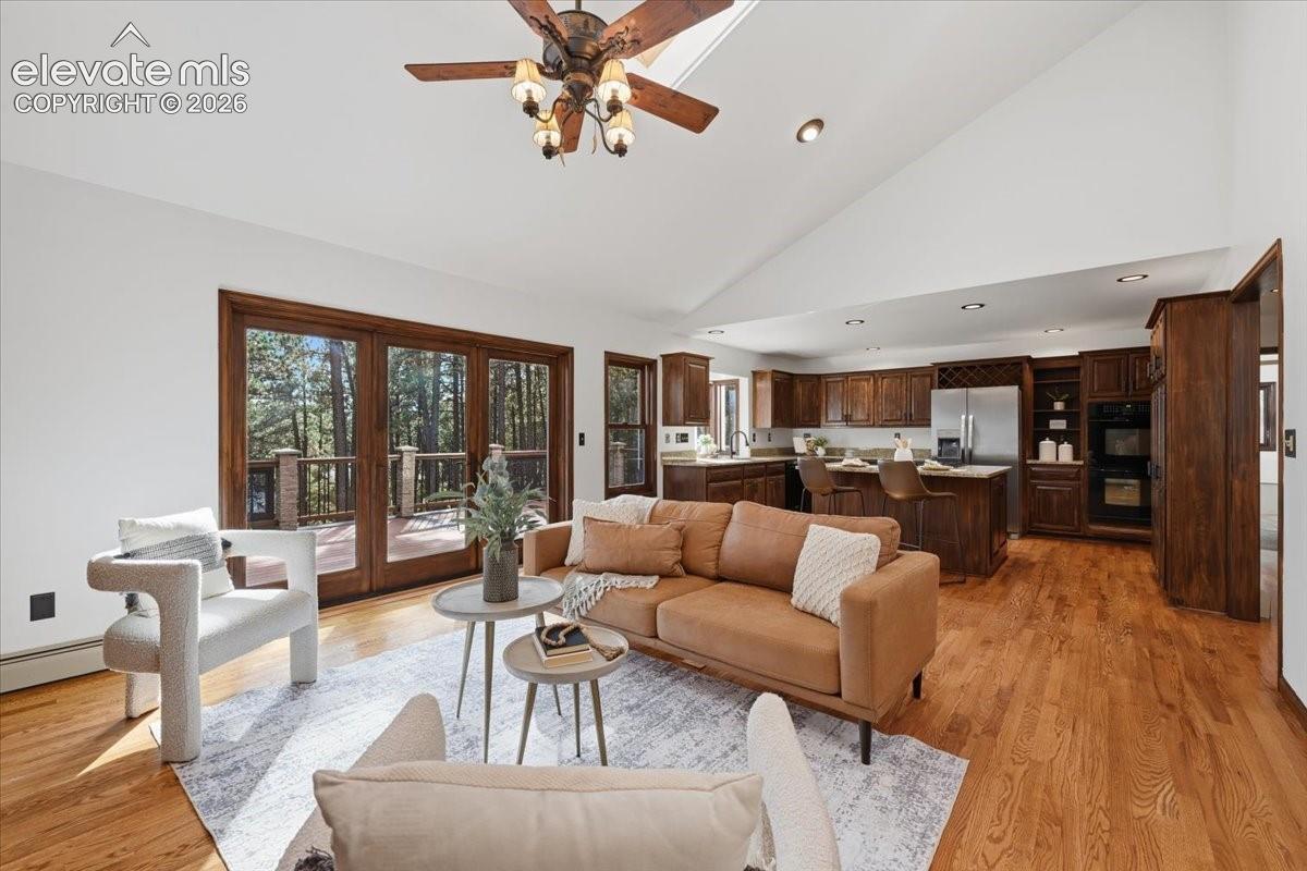 Vaulted white ceiling, wood-finish flooring, built-in double oven, and stainless steel appliances