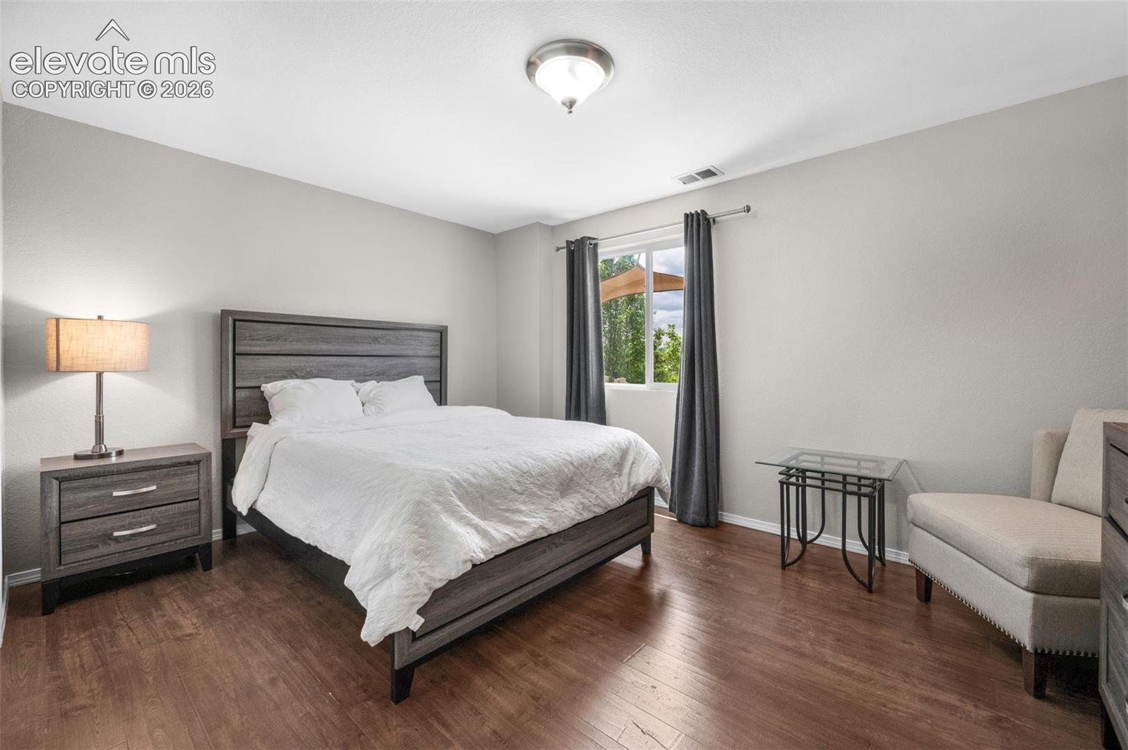 Bedroom #4 Spacious room featuring wood-finish flooring, a large window with drapes, and light gray wall tones