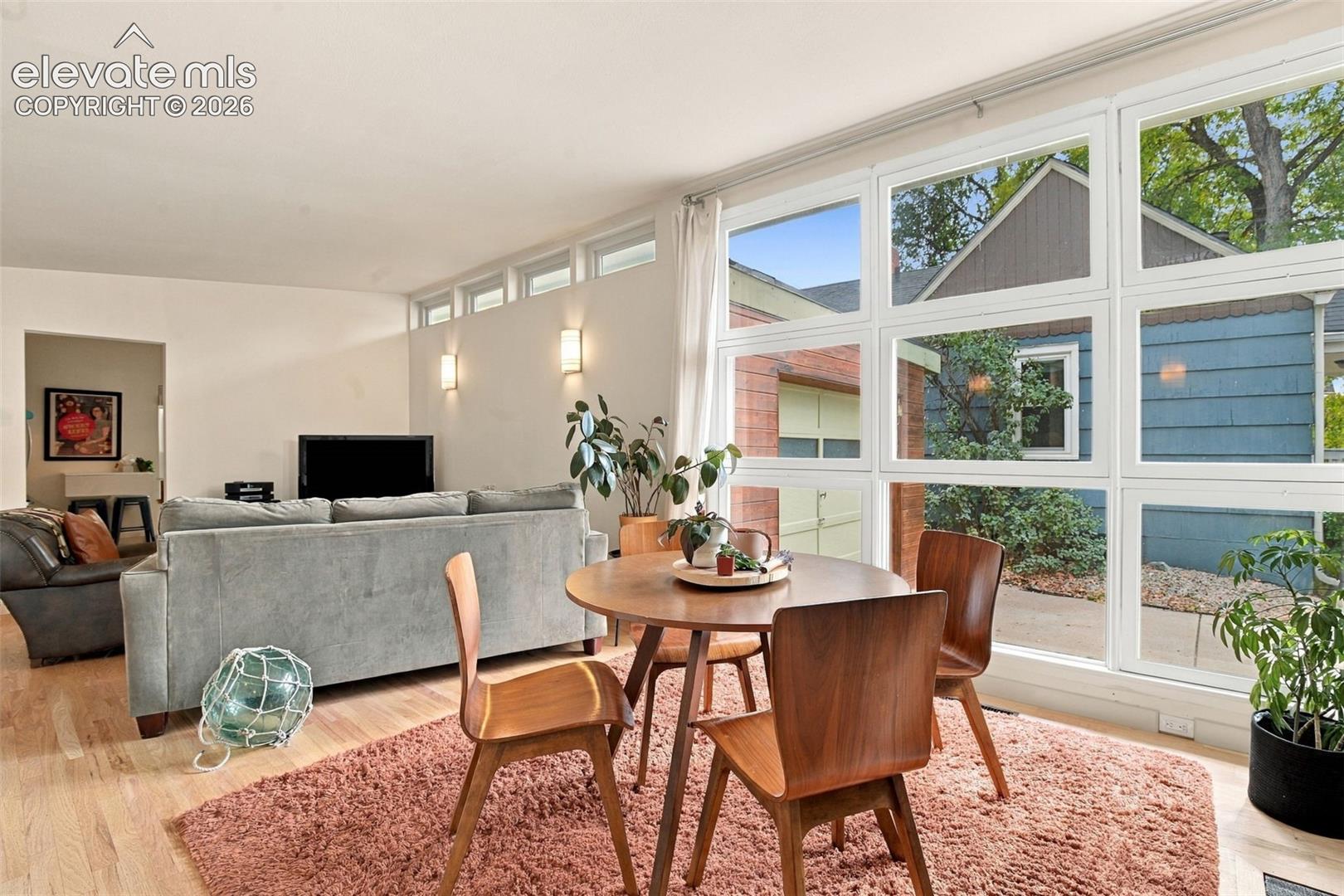 Expansive floor-to-ceiling windows, clerestory windows, wood-finish flooring, and minimalist wall-mounted light fixtures